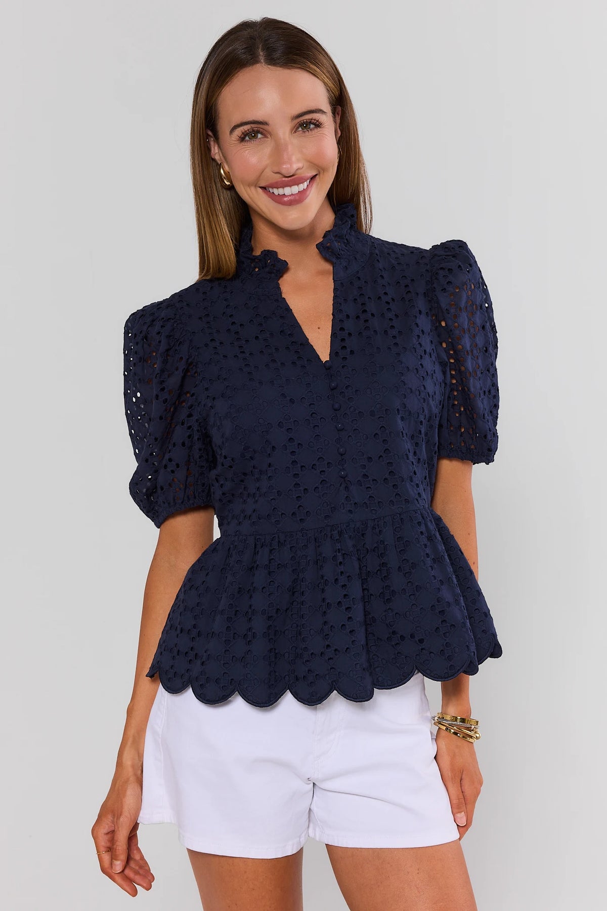 Navy eyelet peplum top with scalloped hem and puff sleeves, styled with white shorts - Front View | Avara