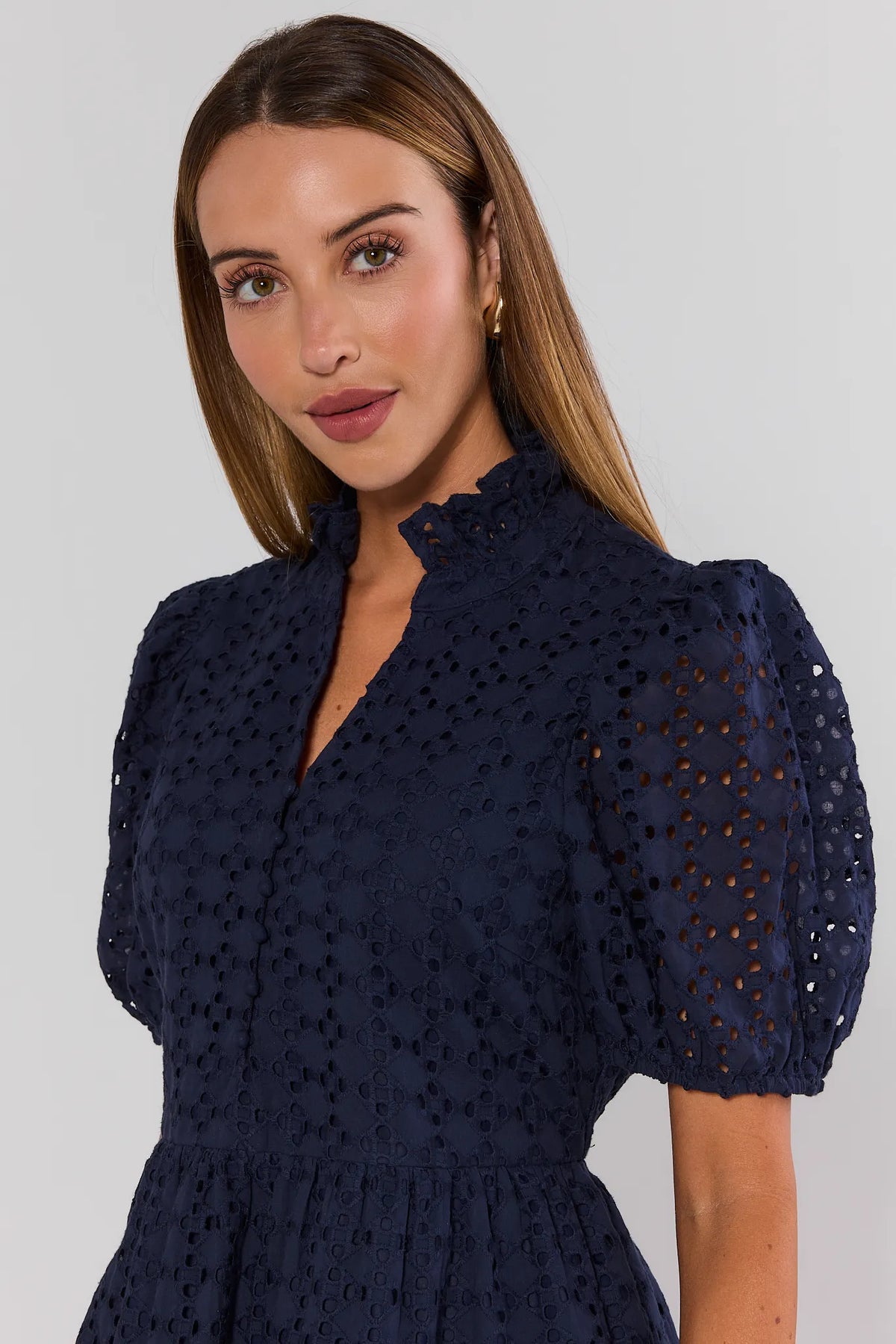 Navy blue eyelet peplum top close-up showing ruffle neckline and allover eyelet embroidery detail | Avara