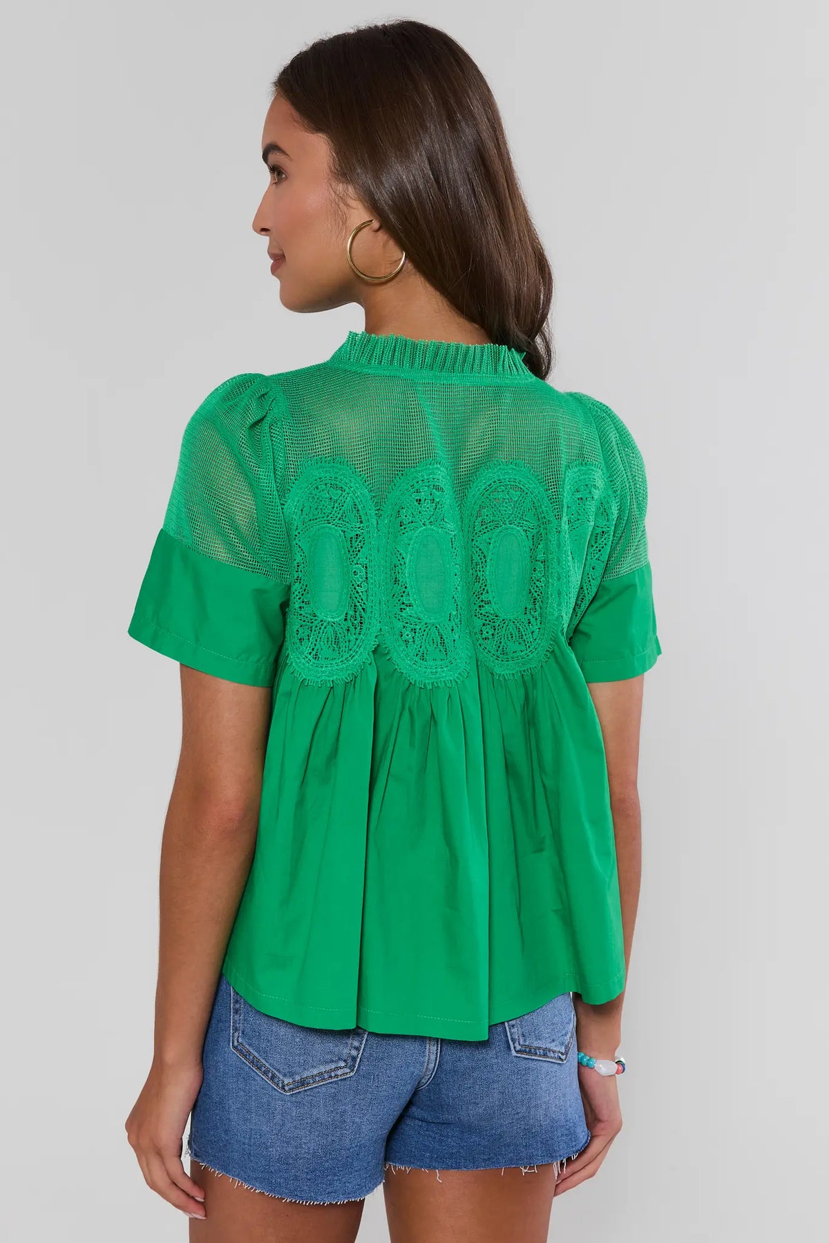Gabrielle Green Peplum Top with embroidered mesh, back view on model with denim shorts | Avara