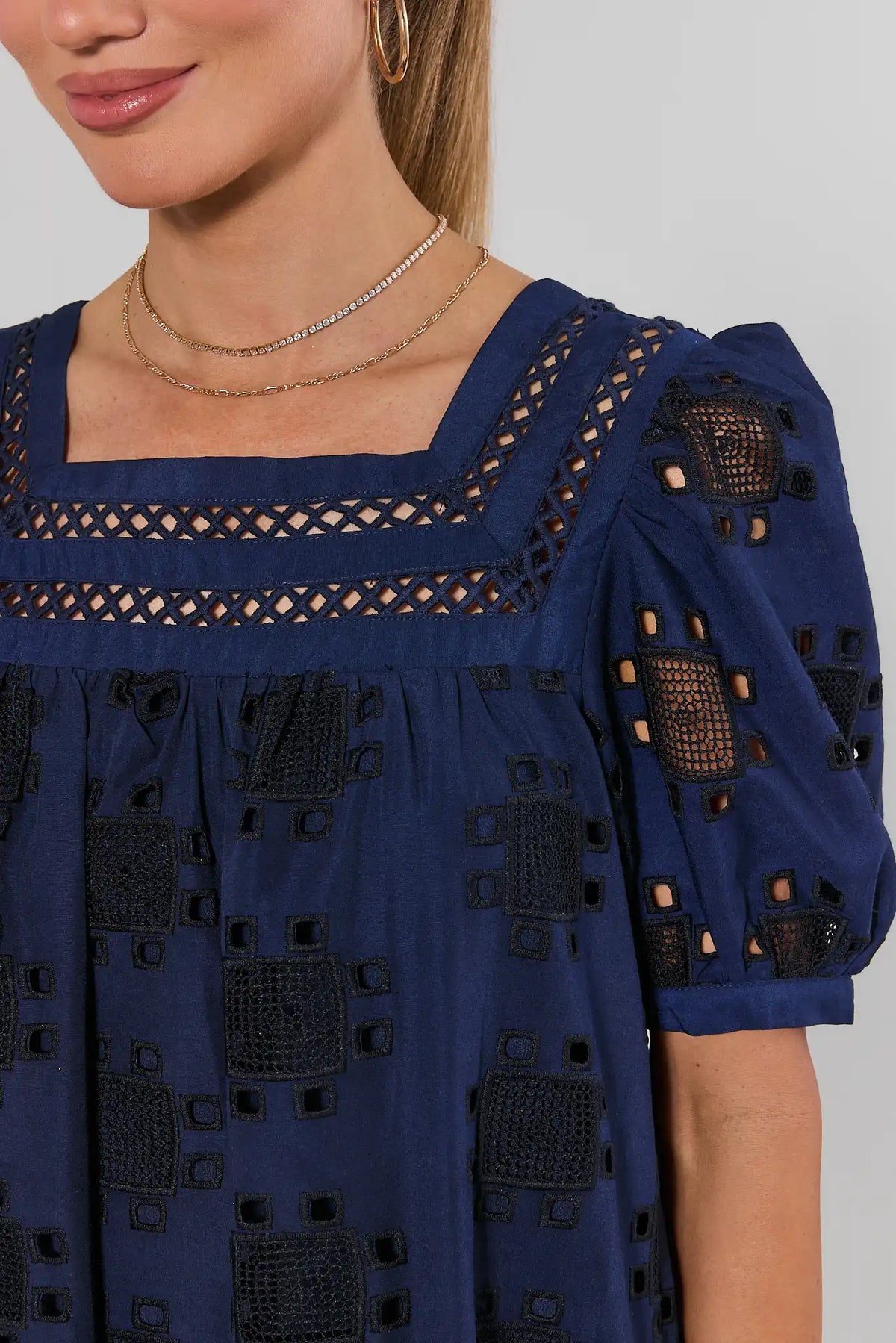 Navy eyelet square neckline close-up with geometric cut-out detail and puff sleeve | Avara