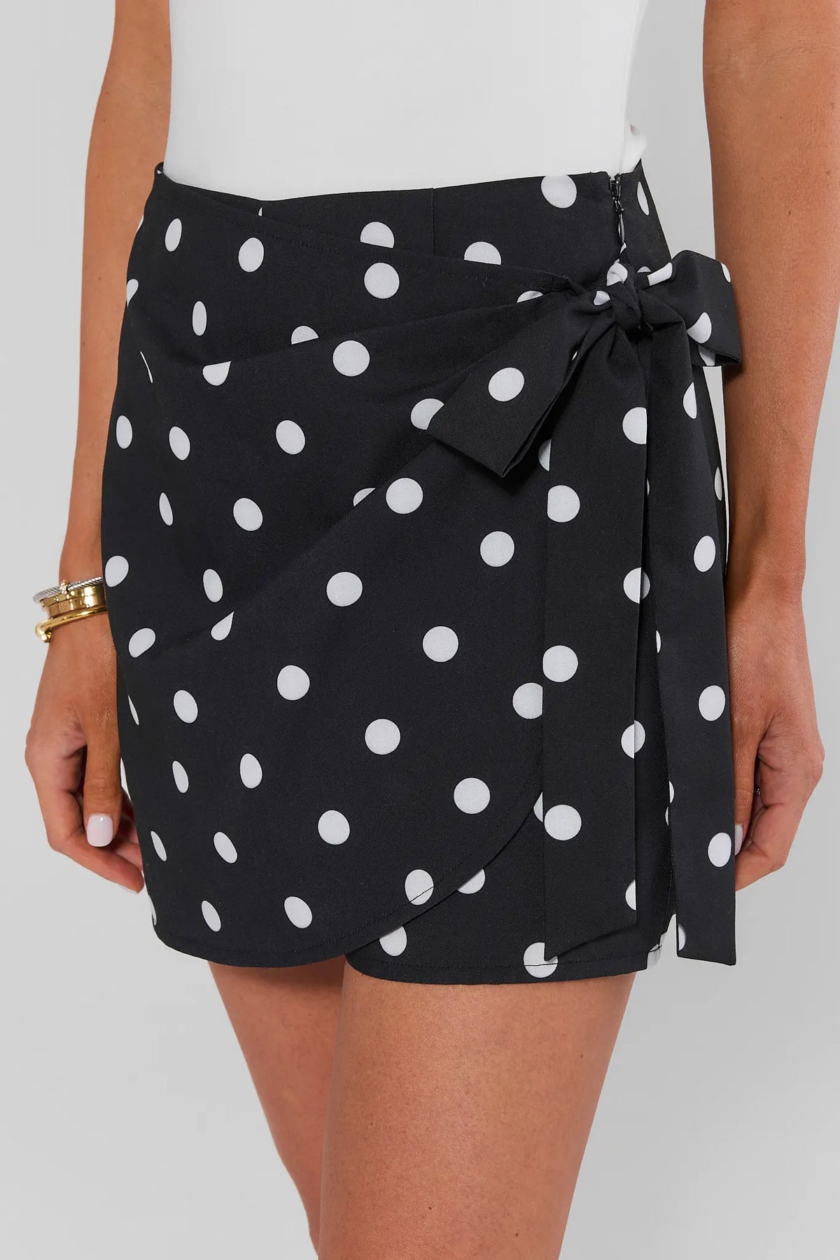 Woman wearing black polka dot mini wrap skirt on a white background