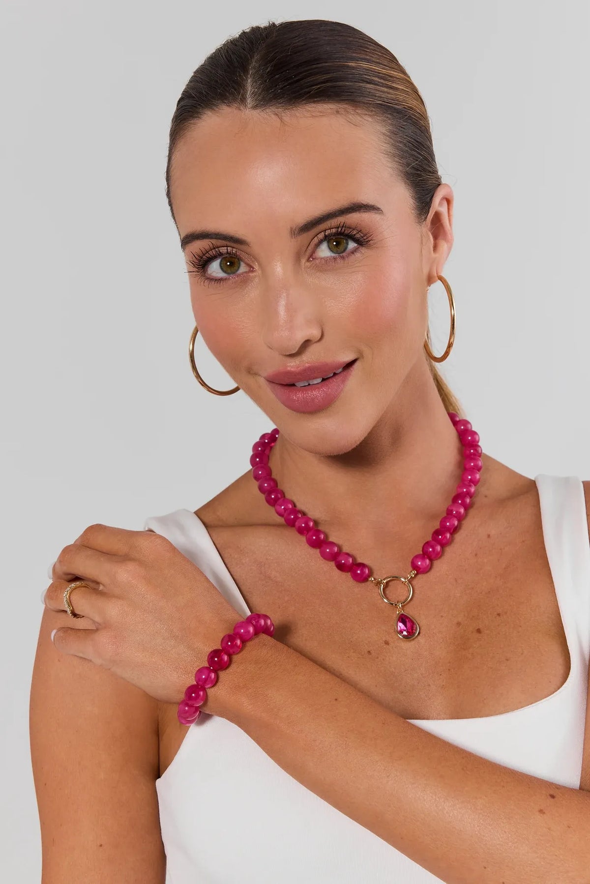 Woman wearing matching Pink Stone Stretch Bracelet and Necklace with gold hoops - On Model | Avara