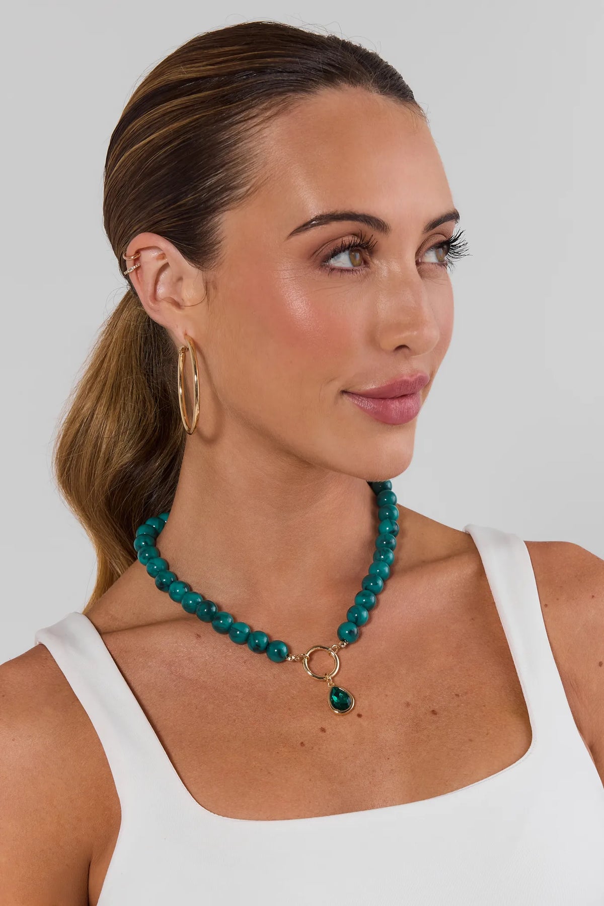 Woman wearing teal rhinestone drop necklace with gold hoops - On Model | Avara