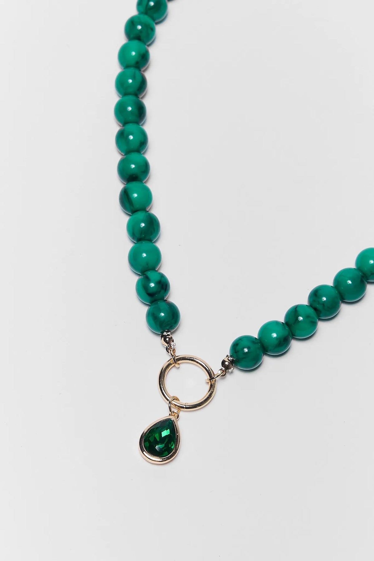 Close-up of teal green beaded necklace with gold circle ring and teardrop rhinestone pendant | Avara