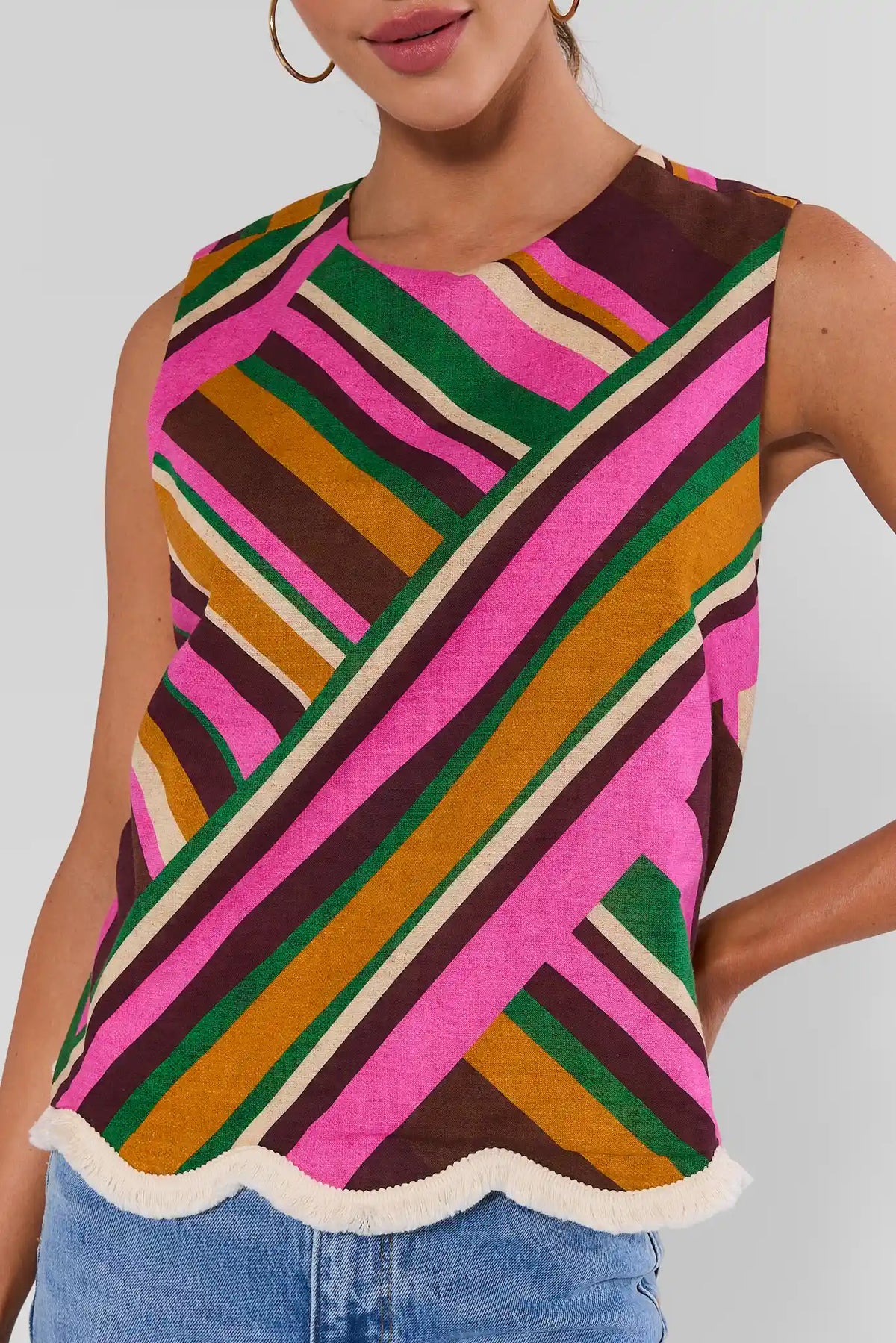 close up Woman wearing Gabby Multi Striped Fringe Trim Tank Top with jeans and gold hoop earrings on white background