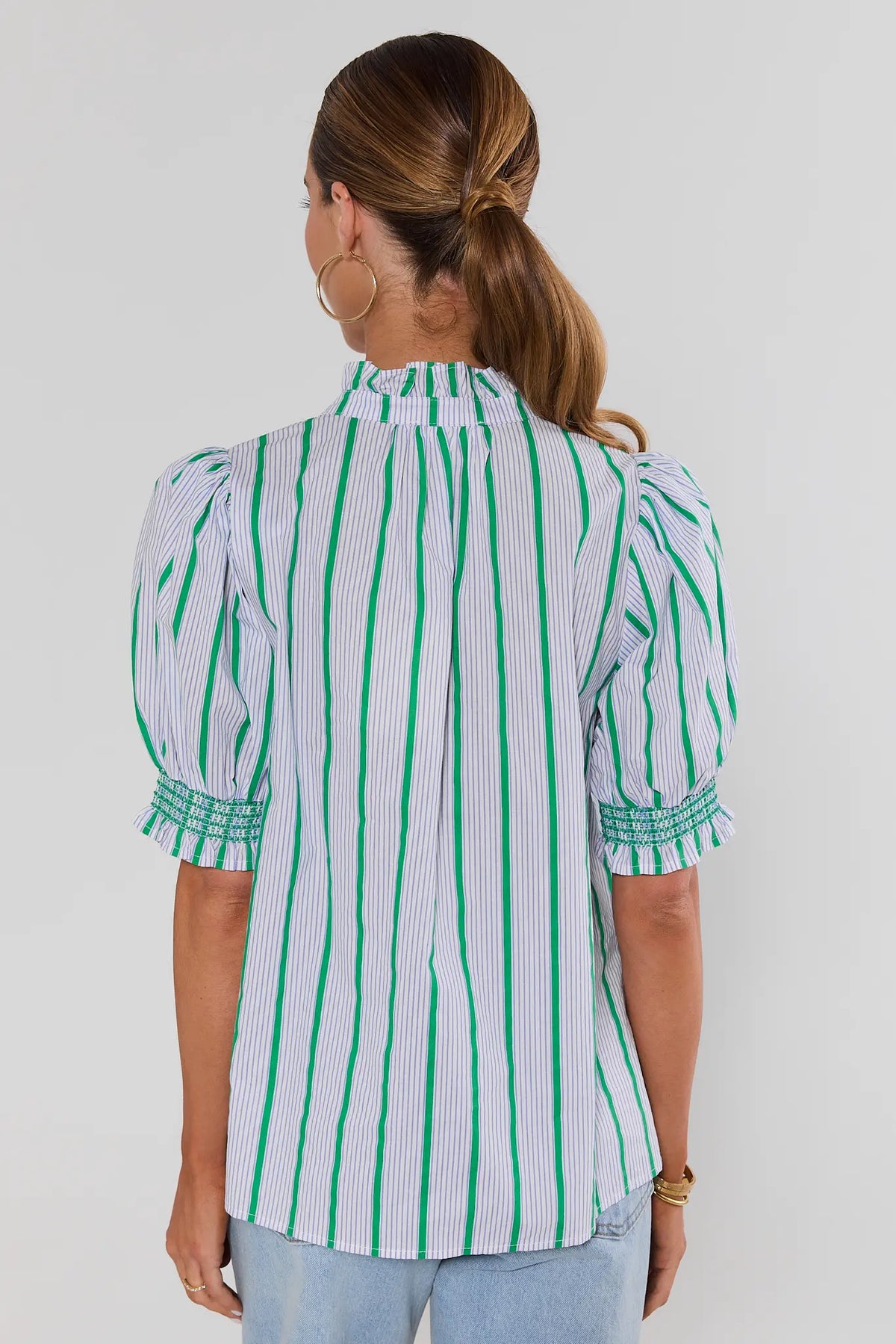 Back view of green striped ruffle button-up top with puff sleeves and smocked cuffs on model | Avara