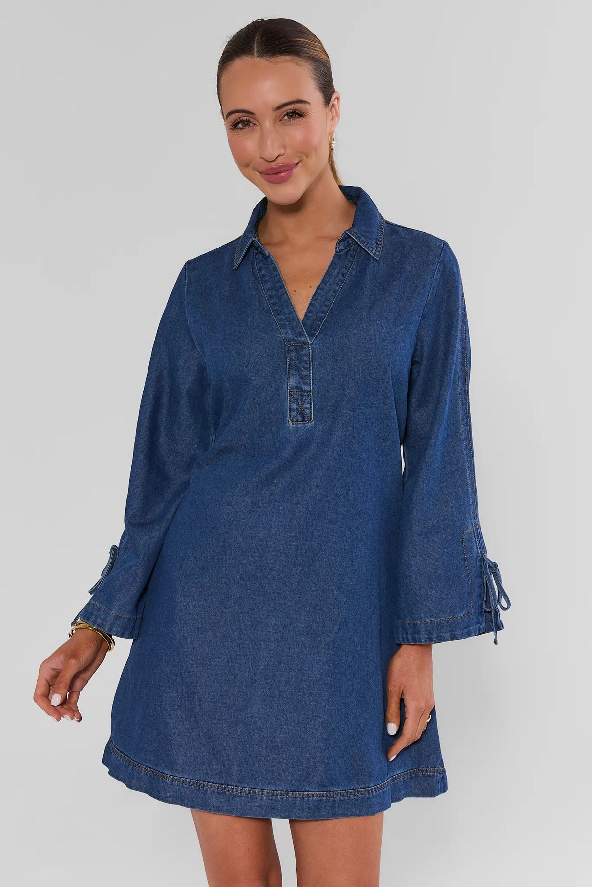 Woman wearing Shay Denim Mini Dress in medium blue wash, V-neck collar, tie sleeves - Front View | Avara
