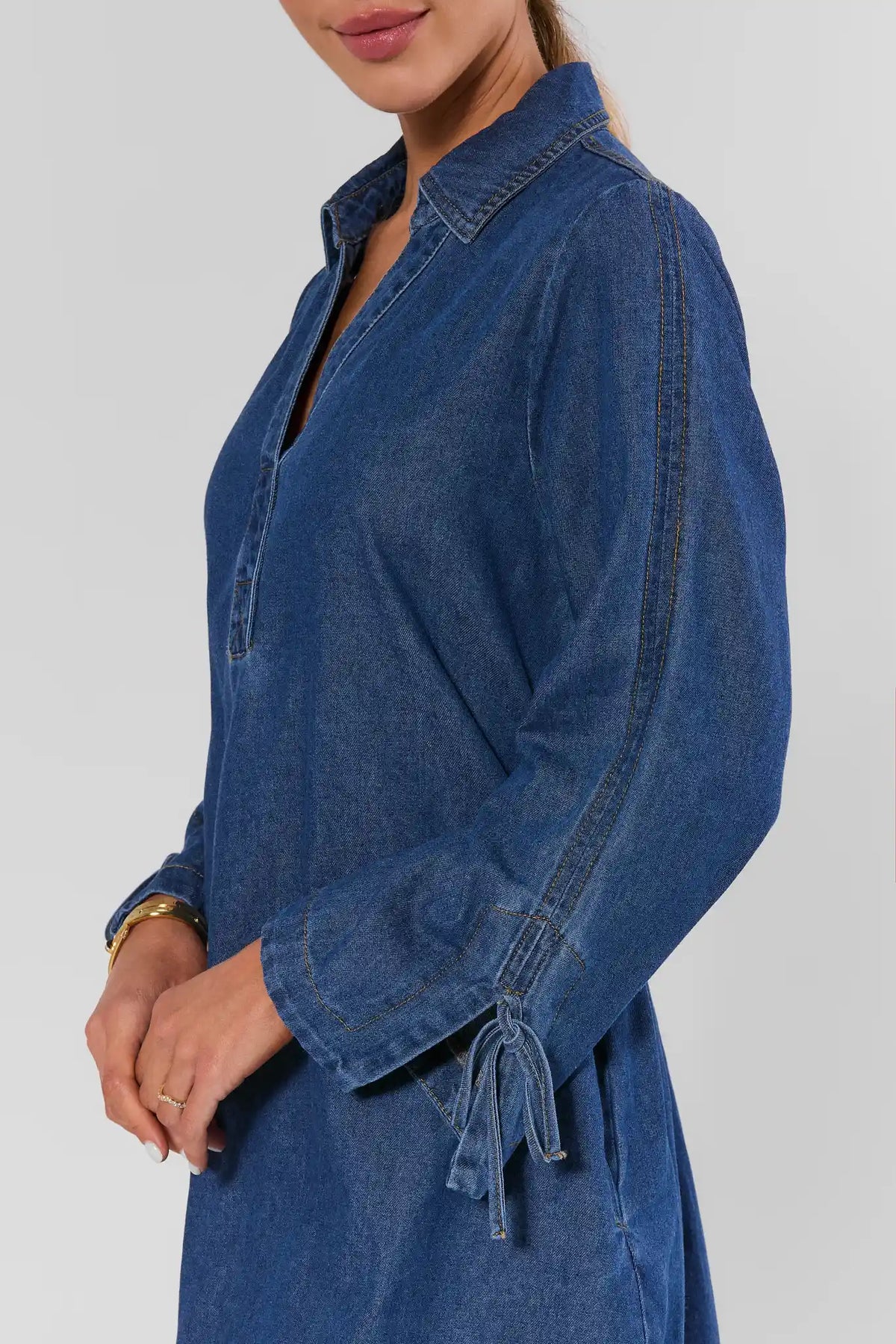 Close-up of Shay Denim Mini Dress tie-cuff sleeve detail and collared V-neckline in medium blue wash | Avara