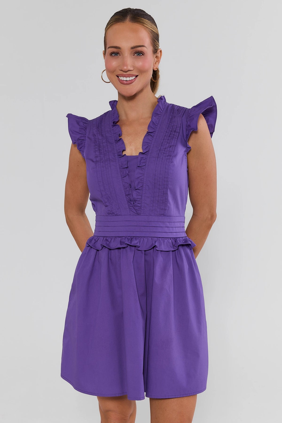 Makayla Purple Flutter Sleeve Short Dress front view, A-line skirt and pleated waistband, styled with white sneakers | Avara