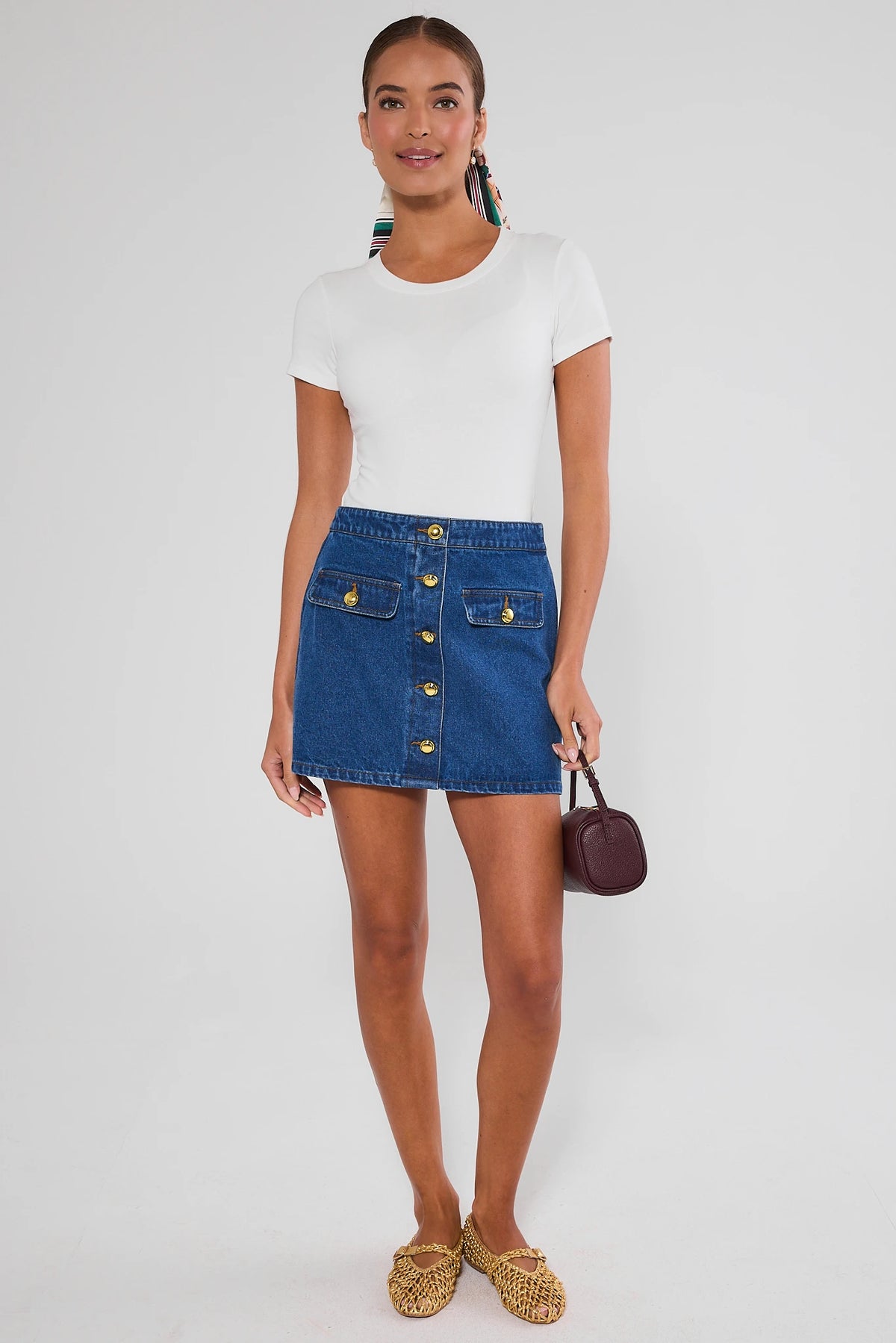 Model in white tee and blue Vickie Denim Button Up Skirt styled with mini bag and woven flats - Full Outfit View | Avara