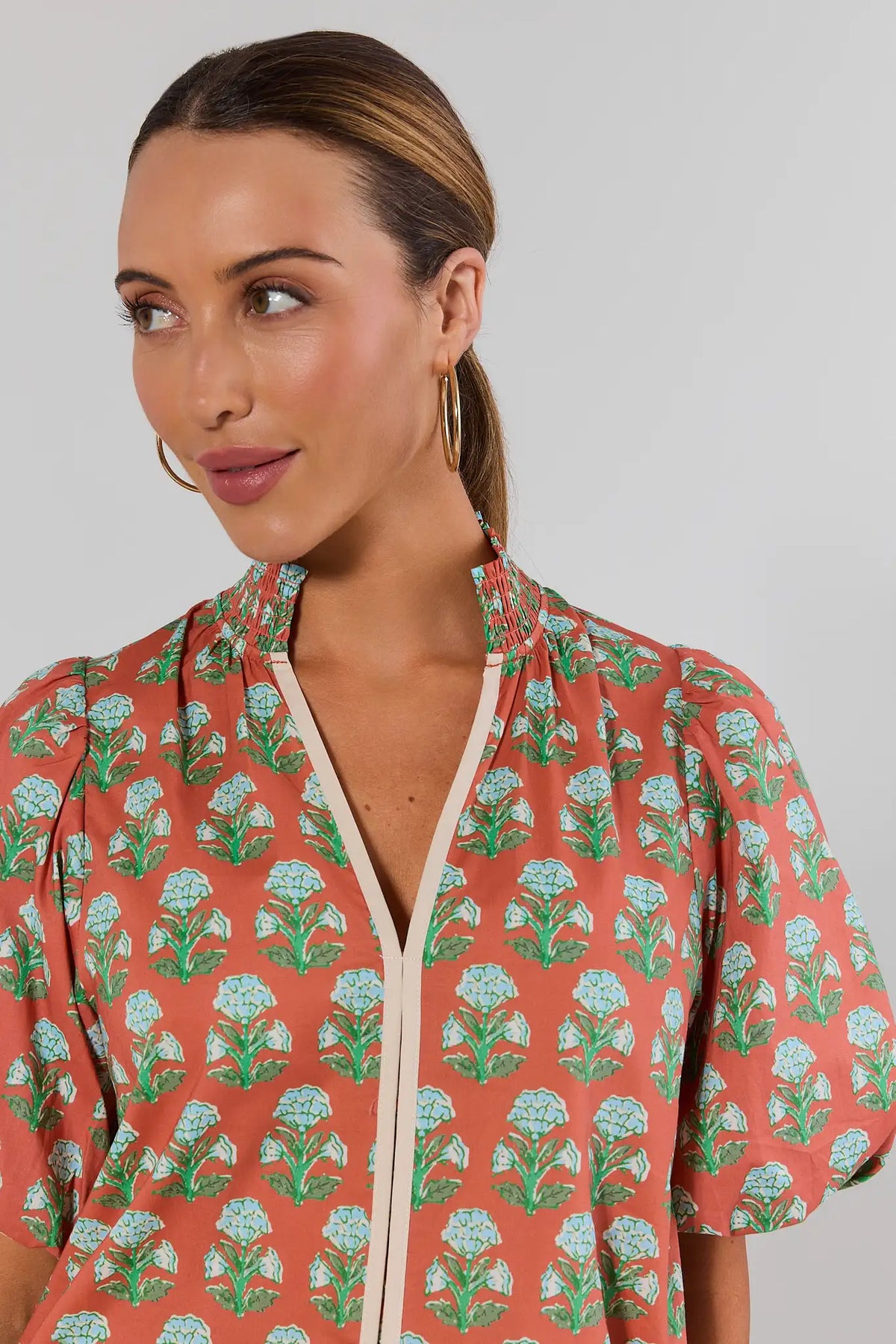 Close-up of THML orange floral top showing smocked neckline detail, cream V-trim, and puff sleeve - Neckline Detail | Avara