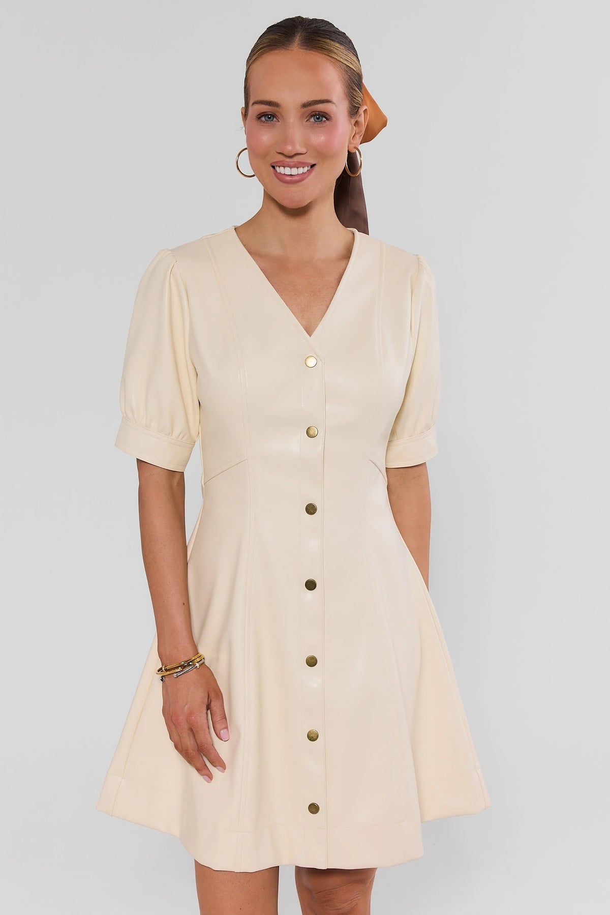 Woman wearing Ivory Faux Leather Short Dress, V-neck gold snap buttons, puff sleeves - Front View | Avara