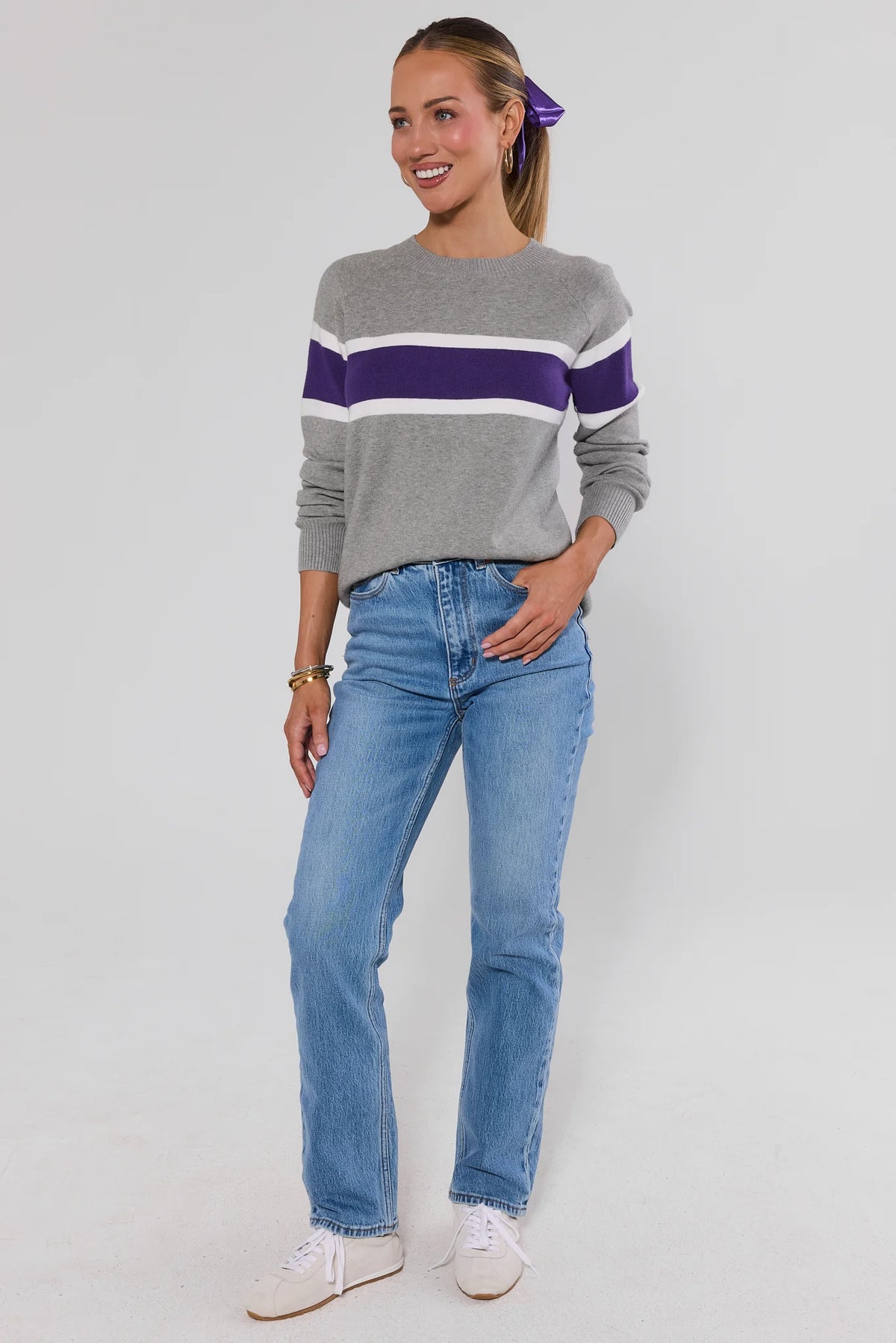 Woman wearing Dylan Purple Stripe Sweater and jeans on a white background