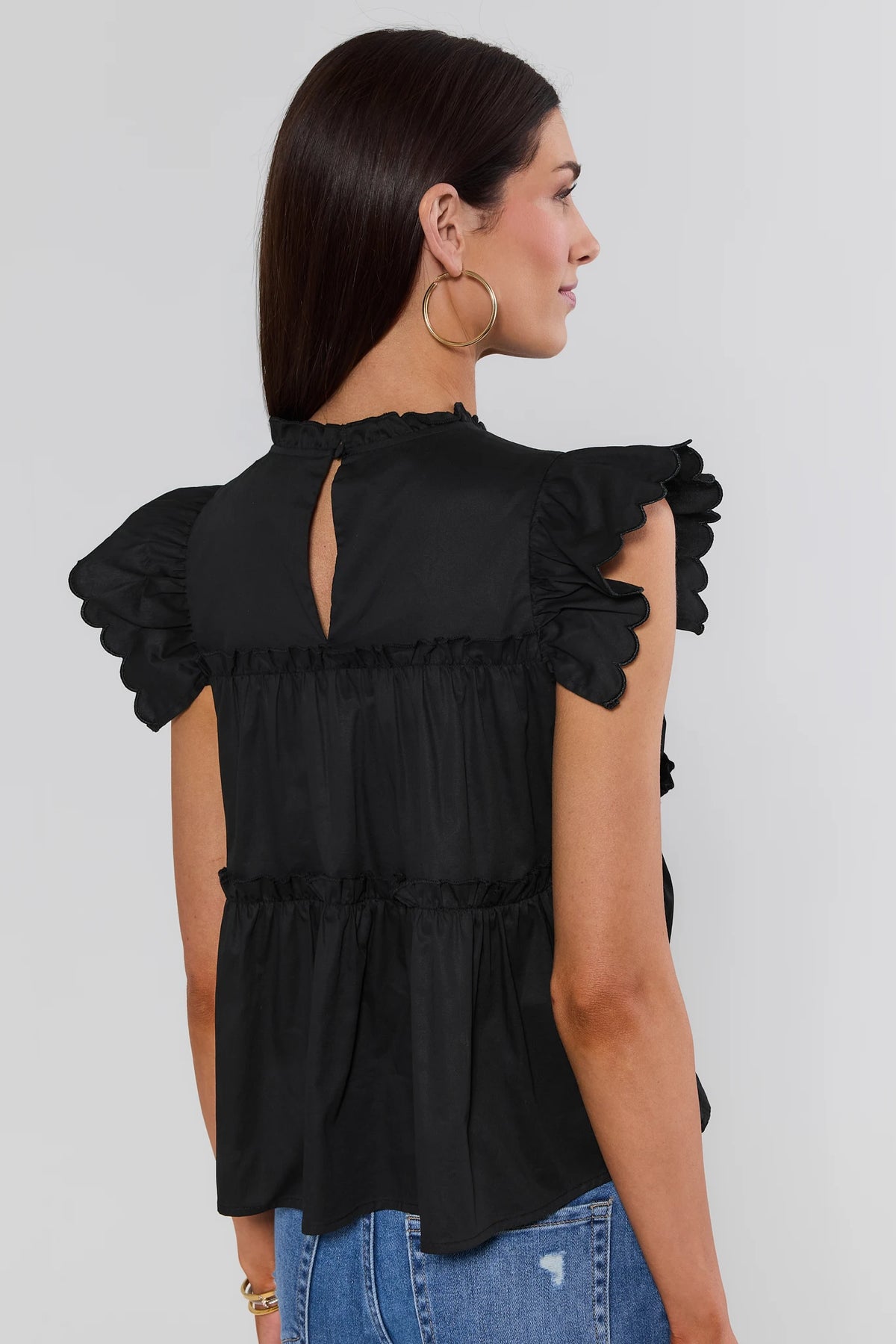 Woman wearing Black Tiered Flutter Sleeve Top showing keyhole back and scalloped sleeves - Back View | Avara
