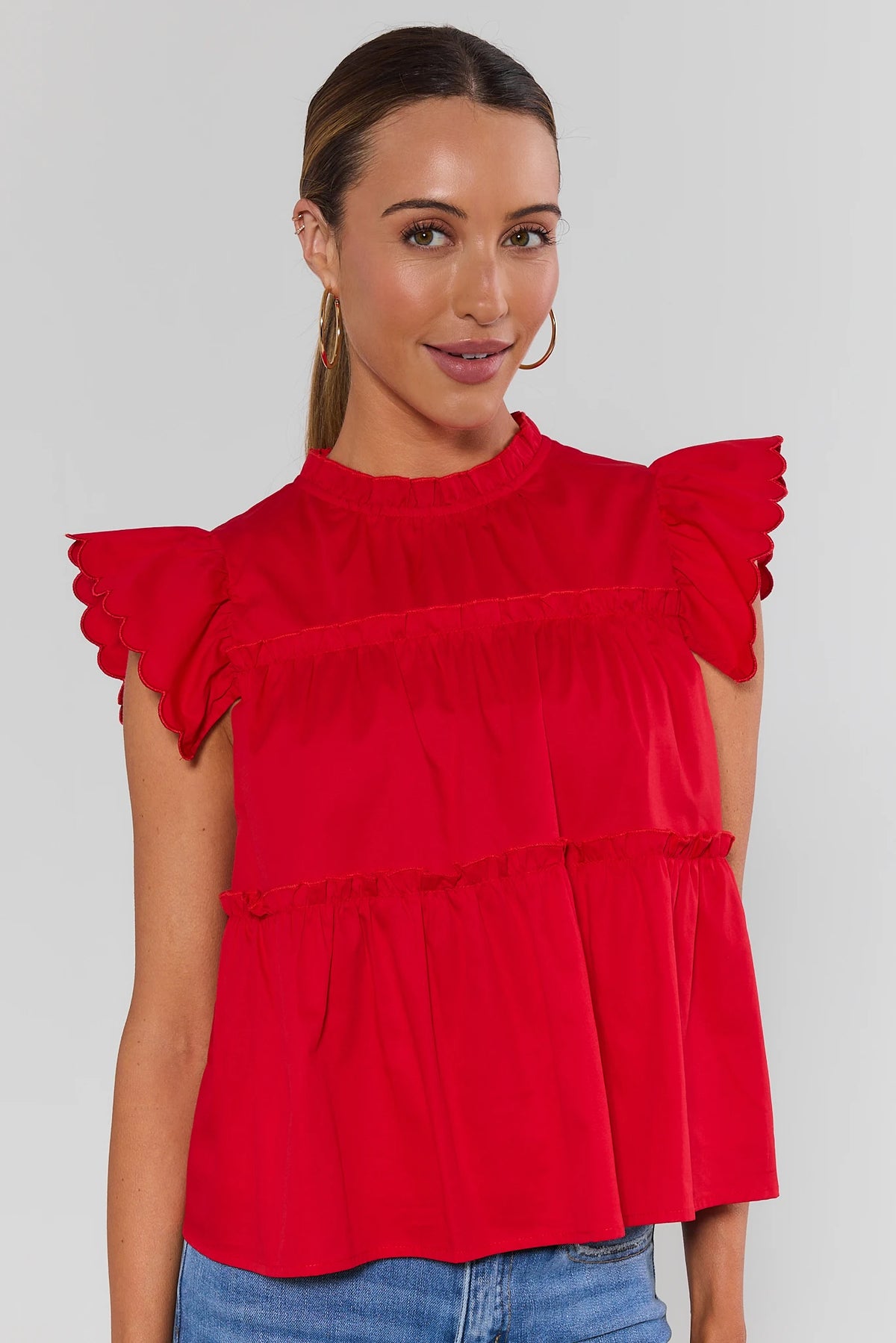 Red tiered flutter sleeve top with scalloped ruffle detail, front angle on model | Avara