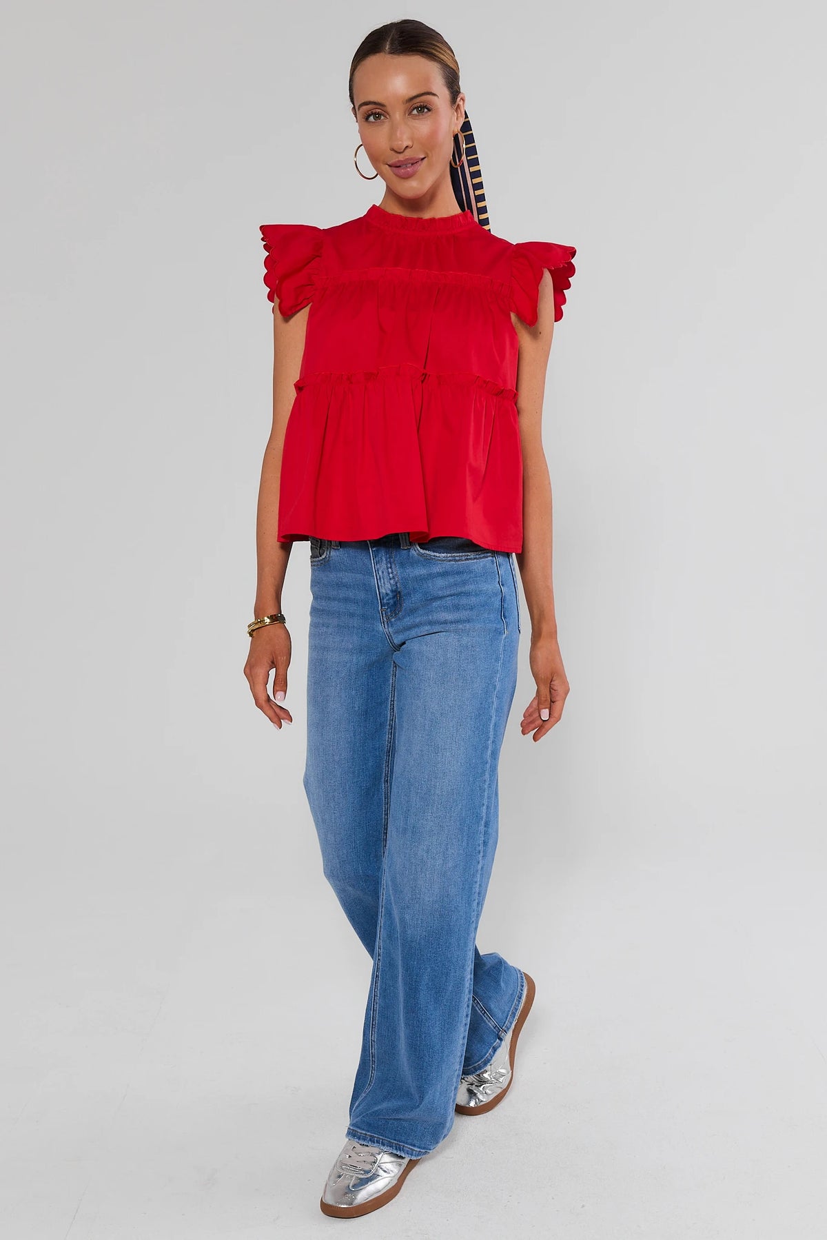 Red tiered flutter sleeve top styled with wide-leg blue jeans and silver flats, full-length front view | Avara