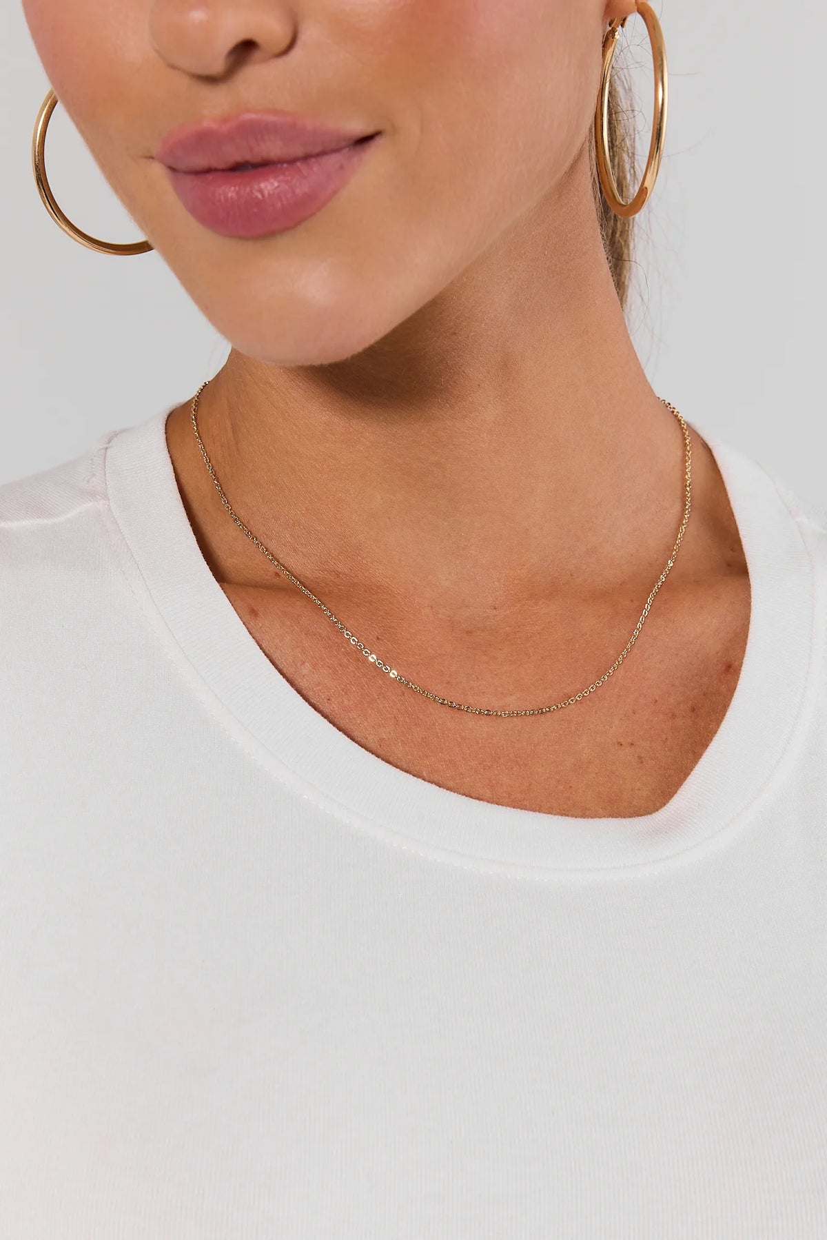 Model wearing dainty gold chain necklace with gold hoop earrings and white top - On Model | Avara