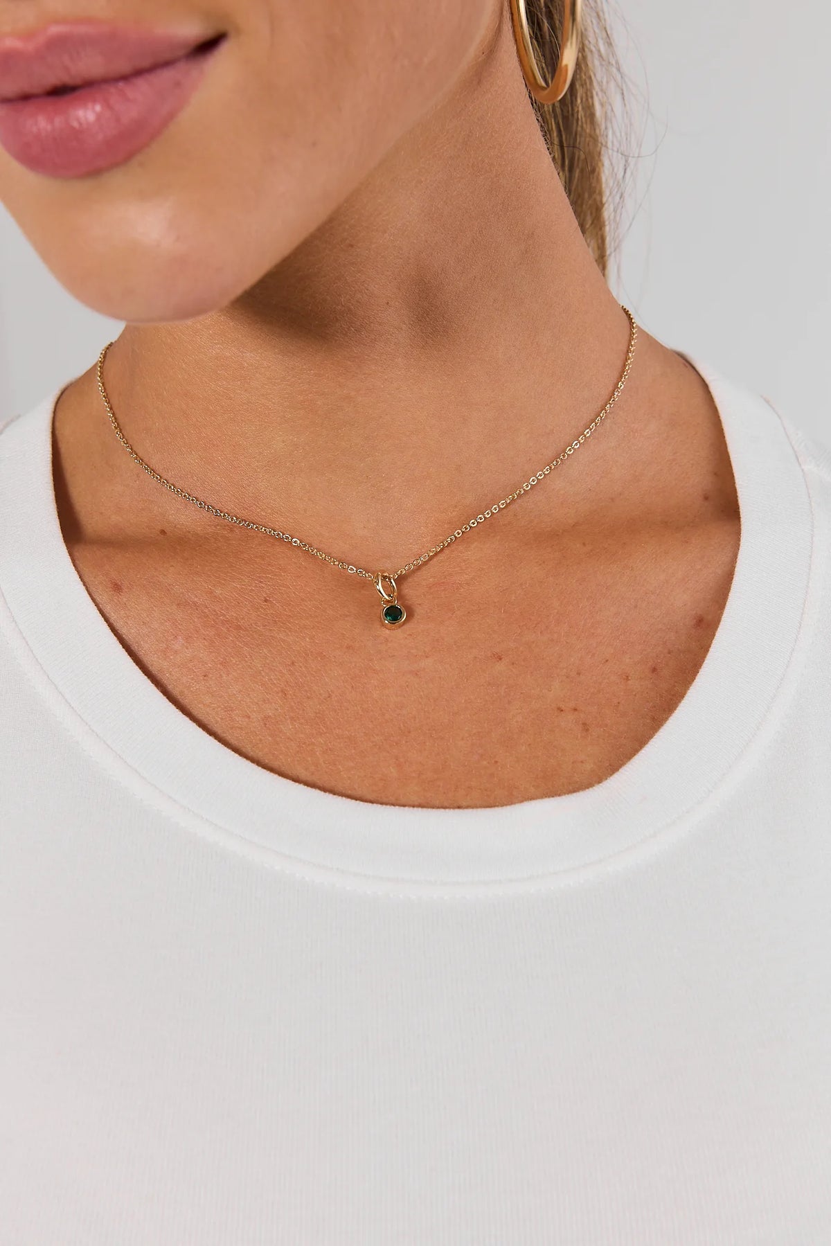 Green rhinestone charm on gold chain necklace worn on model with white top - On Model Detail | Avara