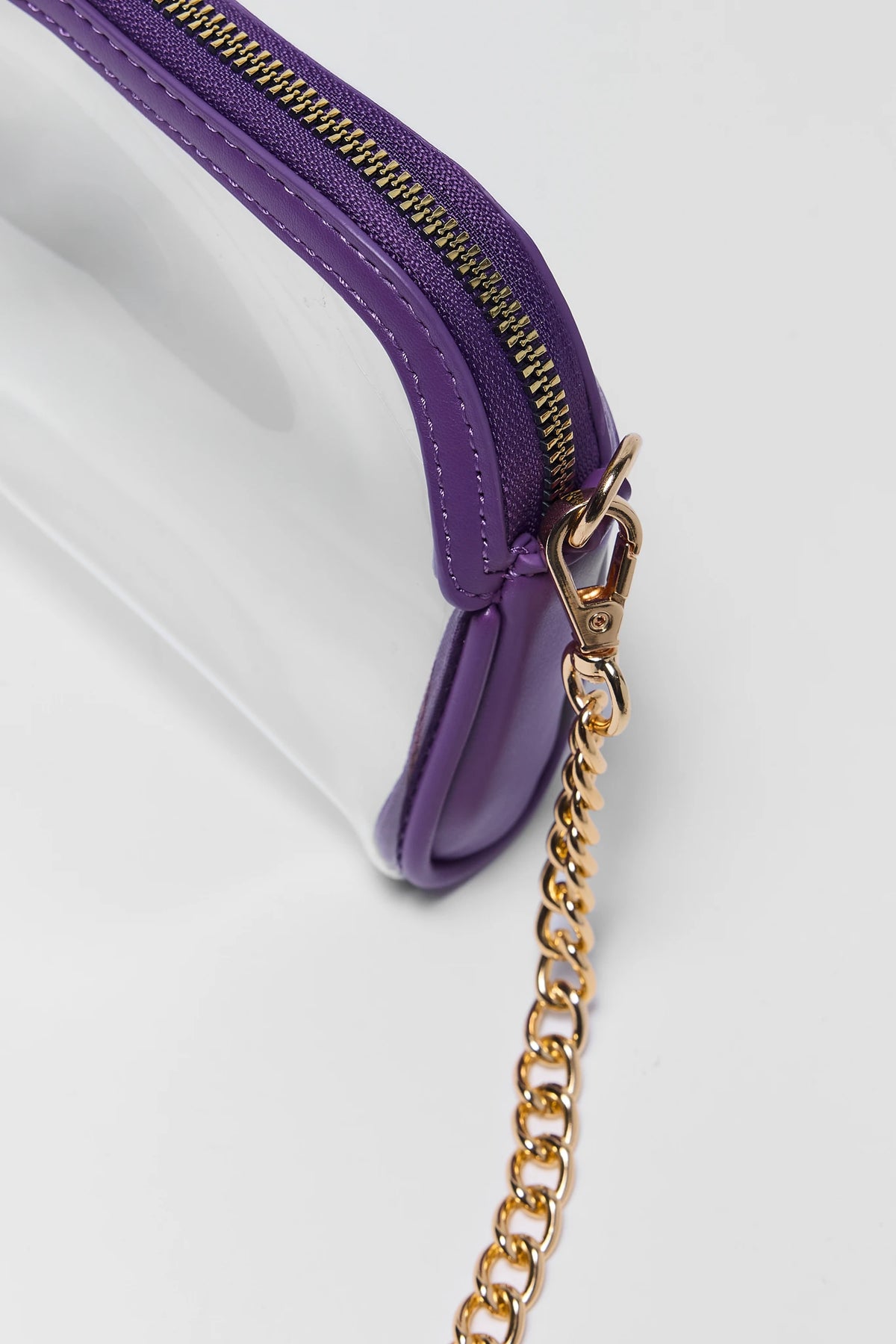 Clear purple bag close-up showing purple zipper trim and gold-tone chain clasp hardware detail | Avara