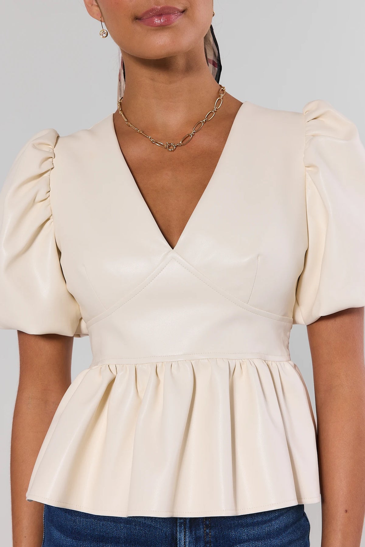 Ivory faux leather peplum top with puff sleeves and V-neckline - Close-Up Detail | Avara