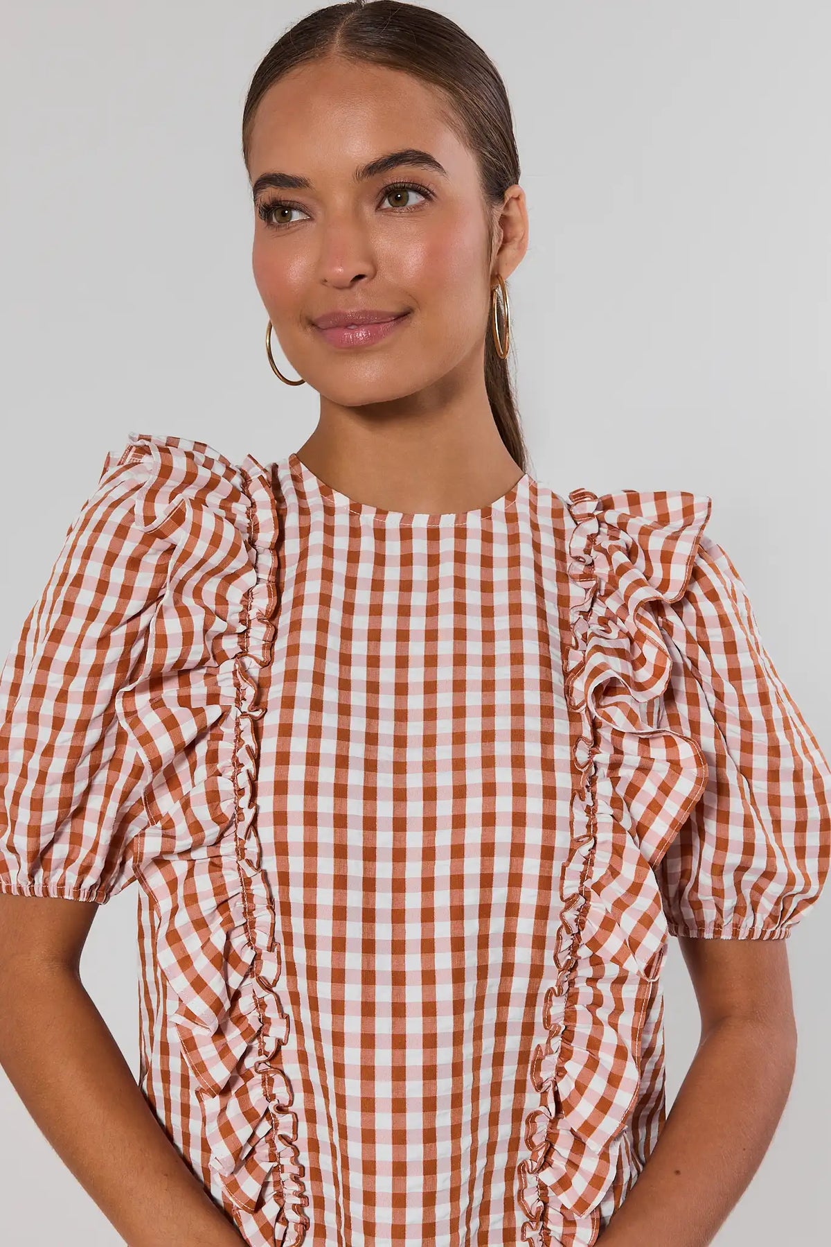 Close-up of orange gingham ruffle blouse showing shoulder ruffle and front ruffle detail with puff sleeves | Avara