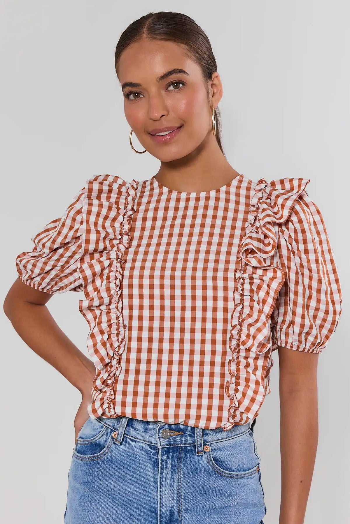 Orange gingham ruffle top with puff sleeves and front ruffle trim, paired with blue jeans - Front View | Avara