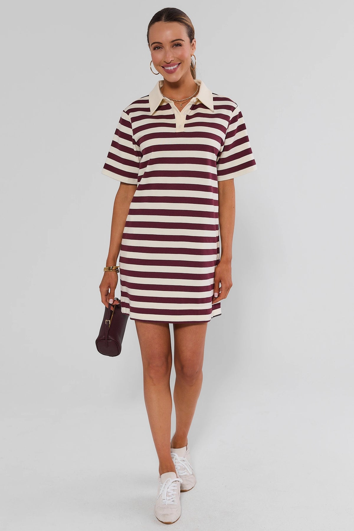Maroon and cream striped polo dress styled with white sneakers and maroon mini bag, full-length | Avara