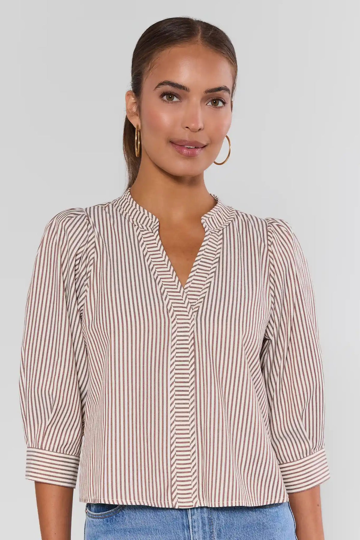 Thea Brown Striped Puff Sleeve Top with split V-neckline, paired with jeans - Front View | Avara