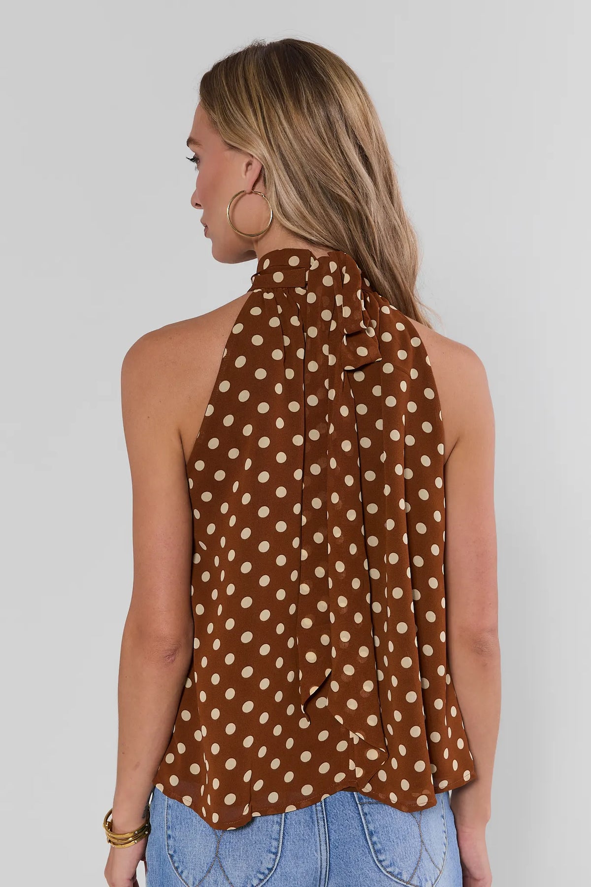 Brown polka dot halter tank top back view showing open back and neck-tie detail, paired with jeans | Avara