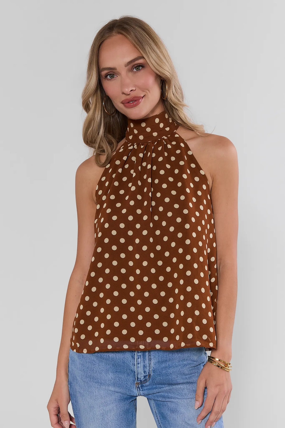 Brown polka dot halter tank top with cream dots, high neck, paired with blue jeans - Front View | Avara