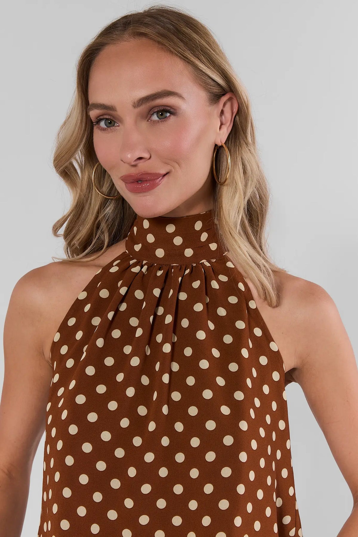 Brown polka dot halter top close-up showing gathered halter neckline detail and cream dot print | Avara