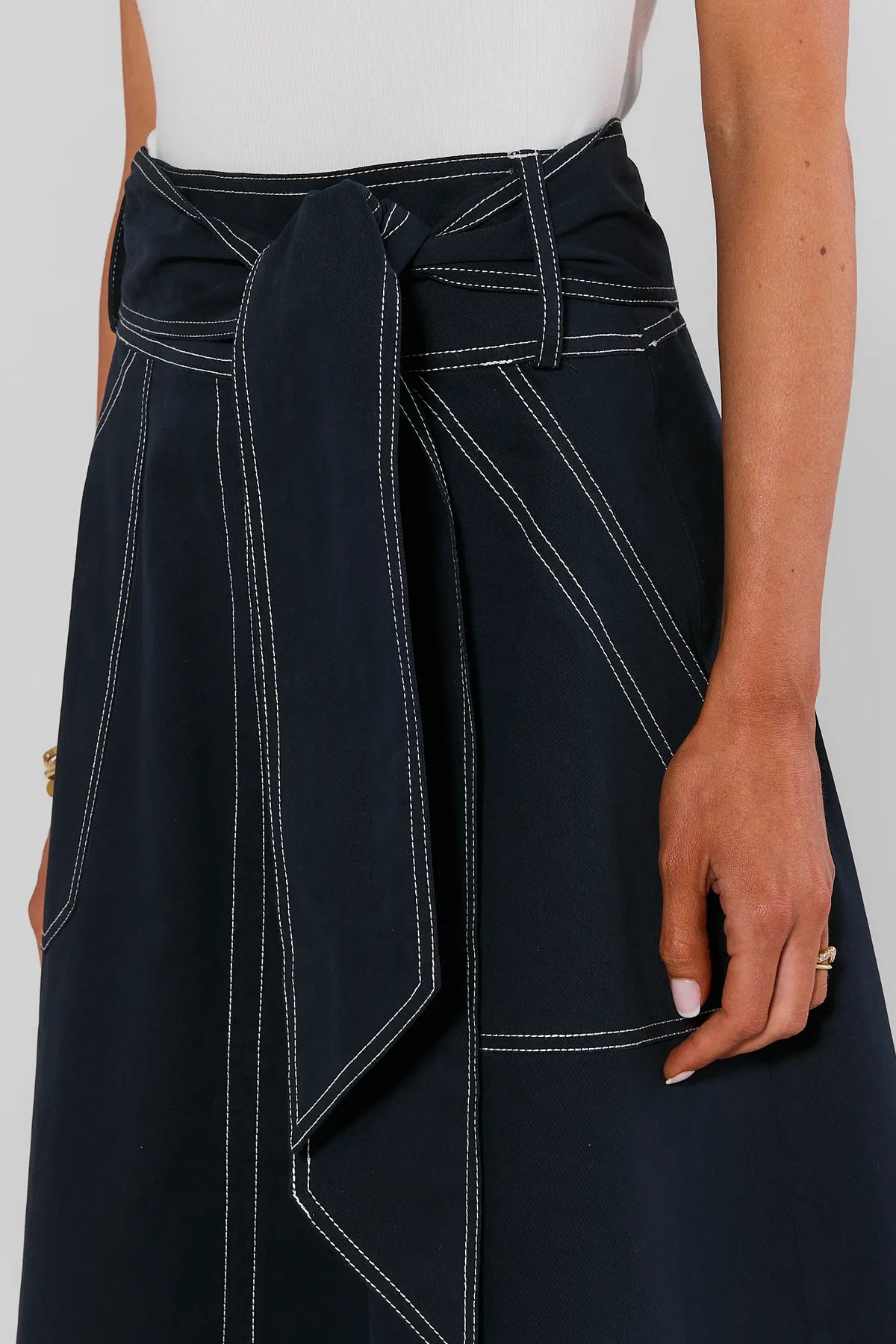 Close-up of navy Charlotte Tie Waist Midi Skirt showing self-tie bow detail and white contrast topstitching | Avara