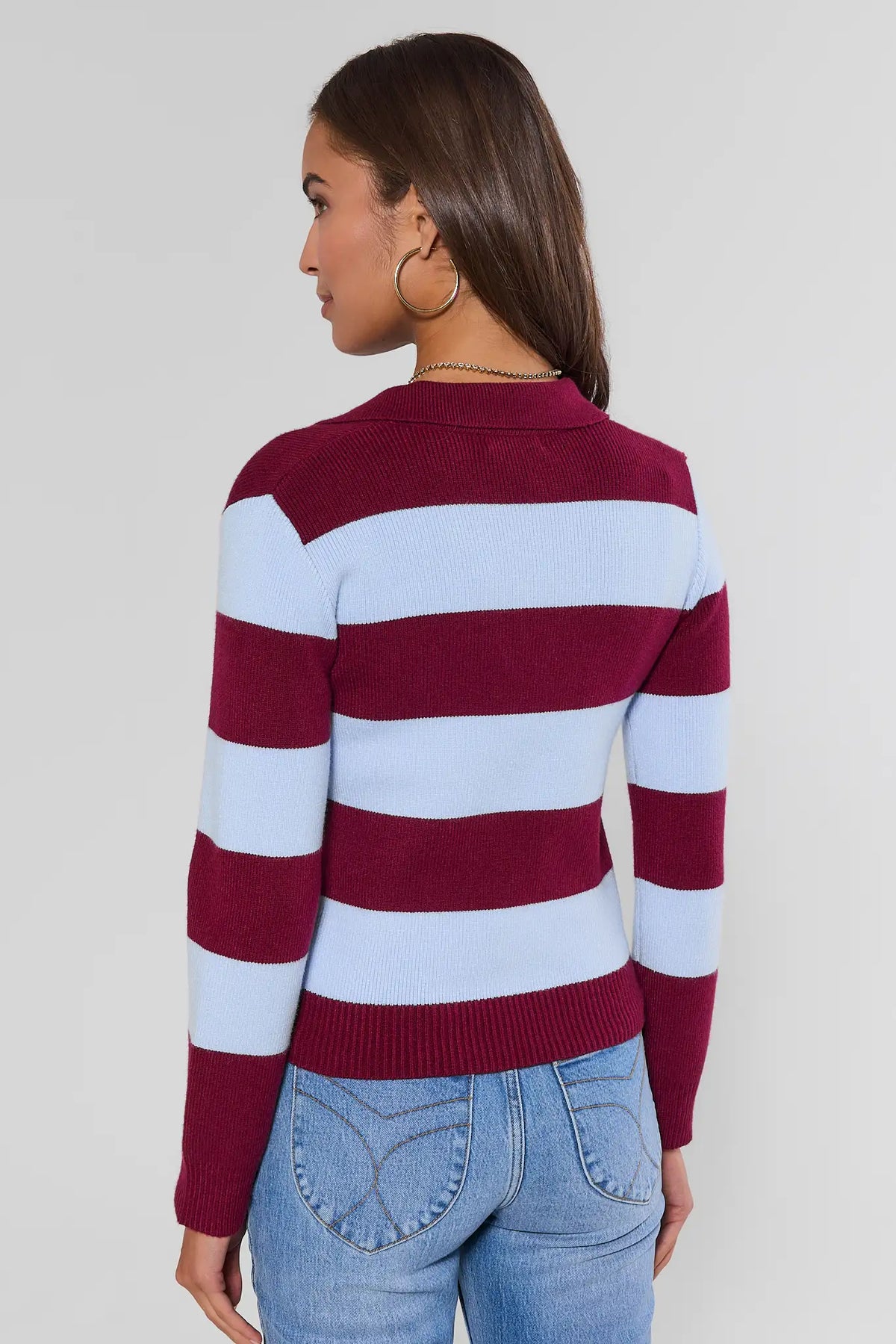 Back view of maroon contrast striped knit sweater showing polo collar and long sleeves, paired with light-wash jeans | Avara