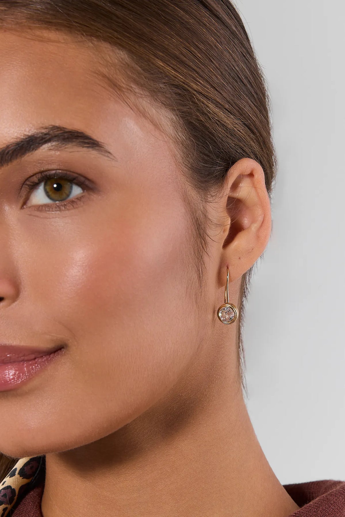 Gold rhinestone drop earring with round clear stone on model - Close-Up Detail | Avara