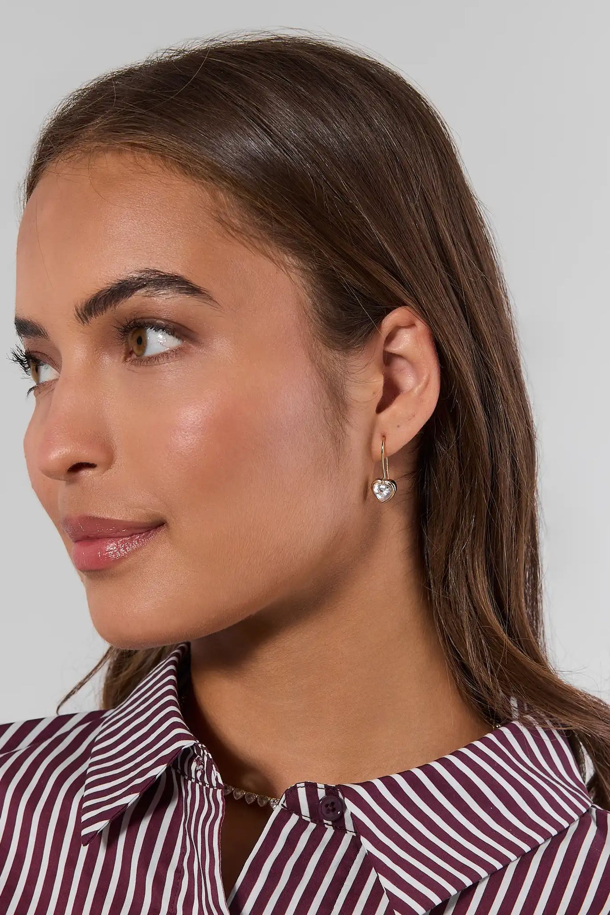 Gold heart rhinestone huggie earring on model, side profile close-up - On Model Detail | Avara