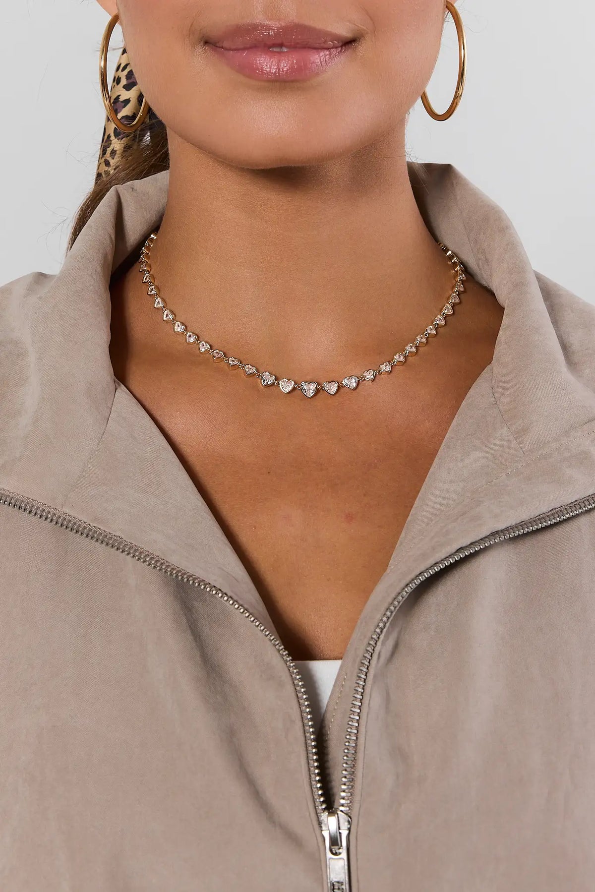 Gold Heart Rhinestone Tennis Necklace On Model - Styled with Beige Jacket & Gold Hoops | Avara