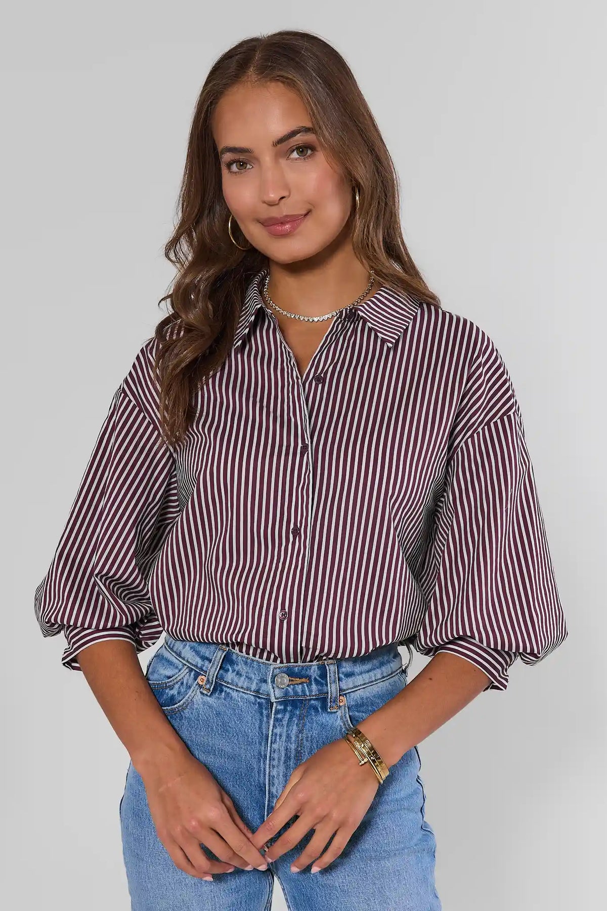 Burgundy striped button-up top with puff sleeves, front view on model with blue jeans | Avara