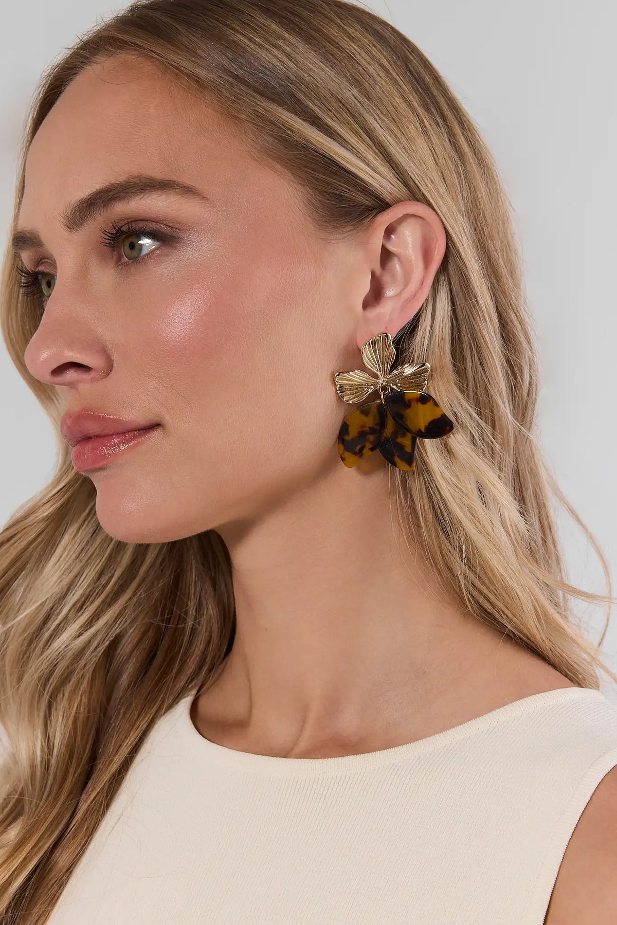 Blonde woman wearing tortoise flower drop earrings with gold fluted top and amber acetate petals - Side Profile | Avara