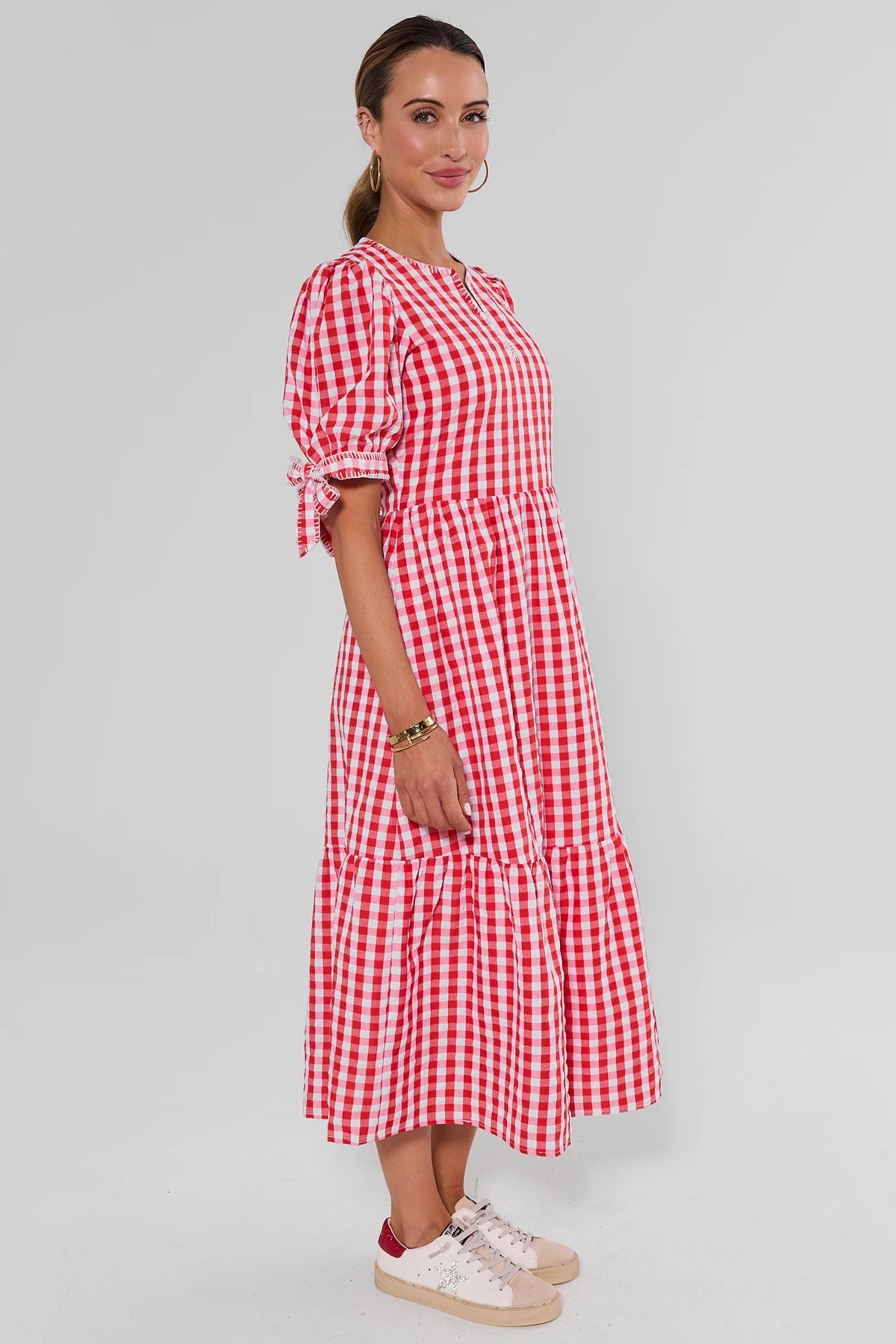 Hazel Red Gingham Midi Dress side view showing tiered skirt and modest below-knee length, styled with sneakers | Avara