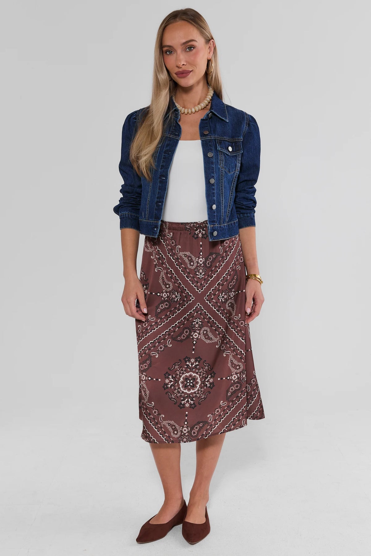 Brown Bandana Print Midi Skirt styled with white top, denim jacket, and brown flats - Full Length On Model | Avara