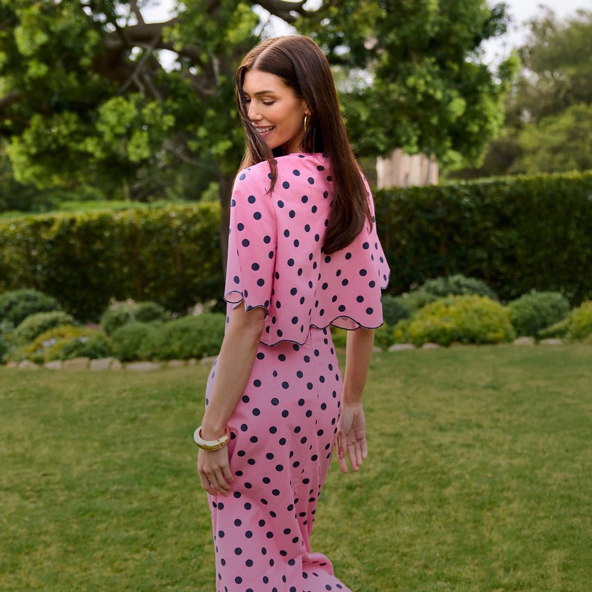 Woman in a pink polka dot dress standing in a garden