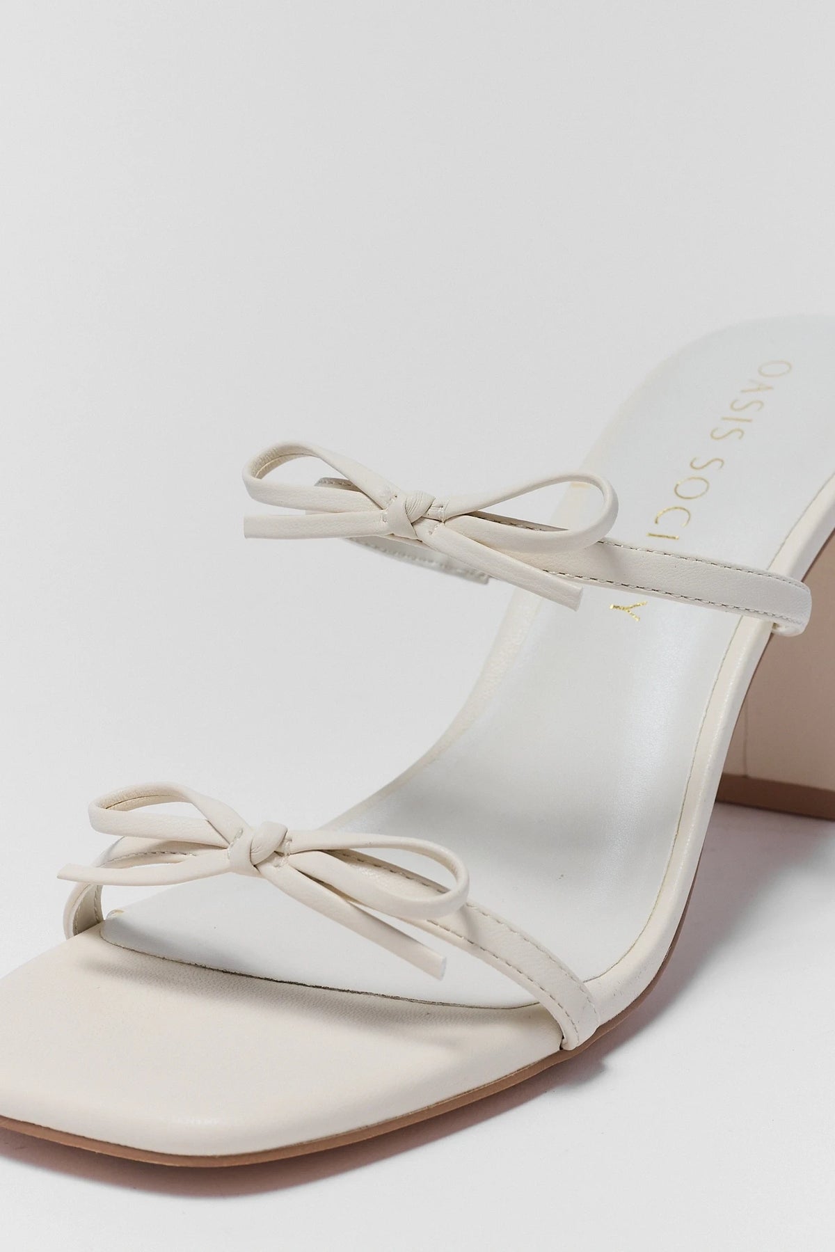 White bow heels close-up showing double strap bow detail and square toe | Avara