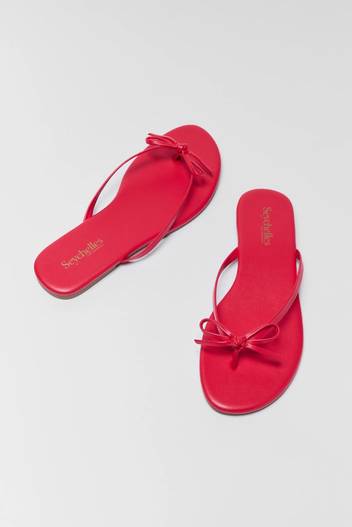 Red bow sandals with a bow on a light gray background - Angled Flat Lay | Avara