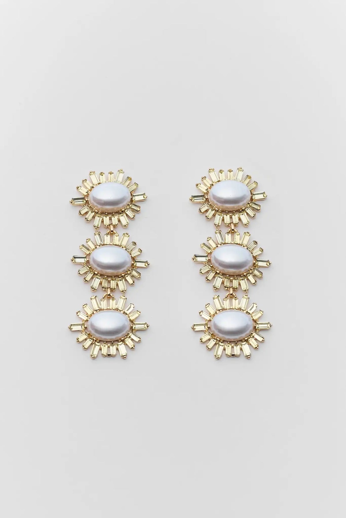 Pair of gold and pearl earrings on a light gray background