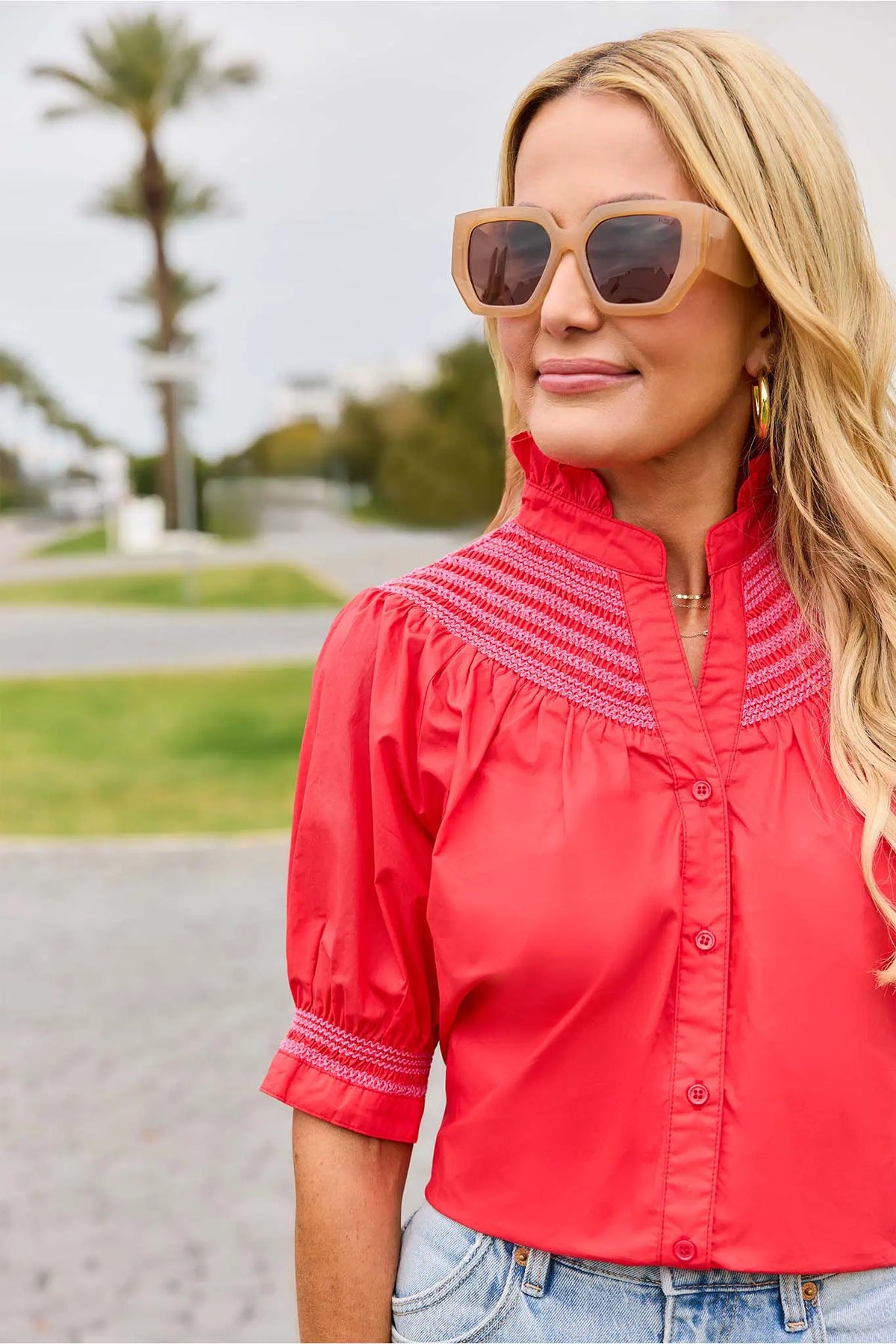 Women's red embroidered top with sunglasses styled outdoors near palm trees - Lifestyle Shot | Avara
