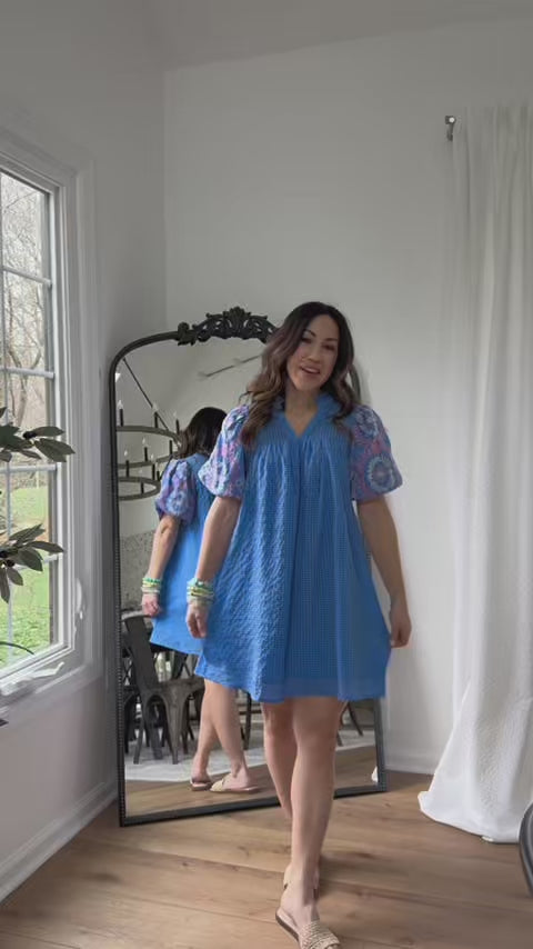 woman wearing blue dress with mirror in background