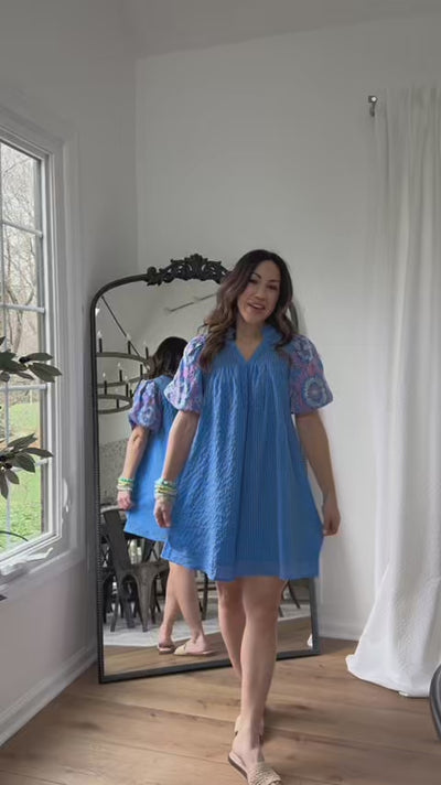 woman wearing blue dress with mirror in background