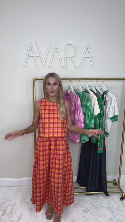 woman wearing orange and pink estie plaid set with a rack of clothing behind her