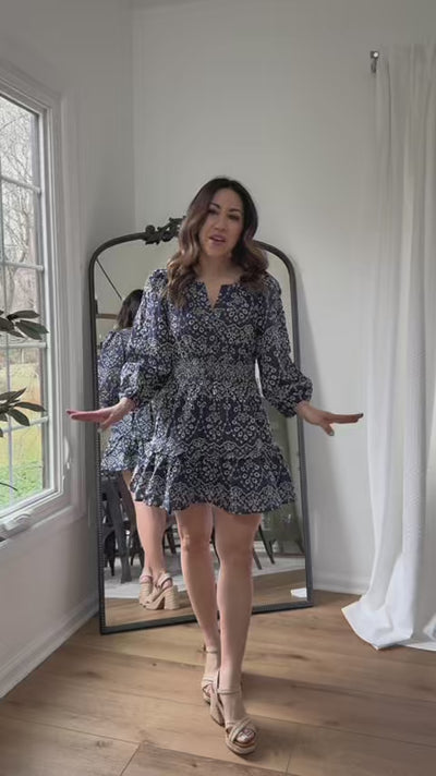 Woman wearing emmie navy embroidered dress with a mirror in the background