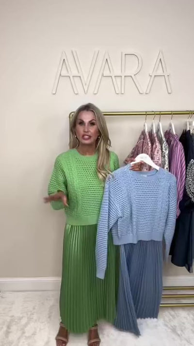 woman wearing green gabbie two piece dress with a rack of clothing behind her